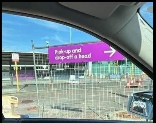 Sign reads "Pick-up and drop-off a head" with an arrow pointing right, seen through a car window, indicating a humorous typo