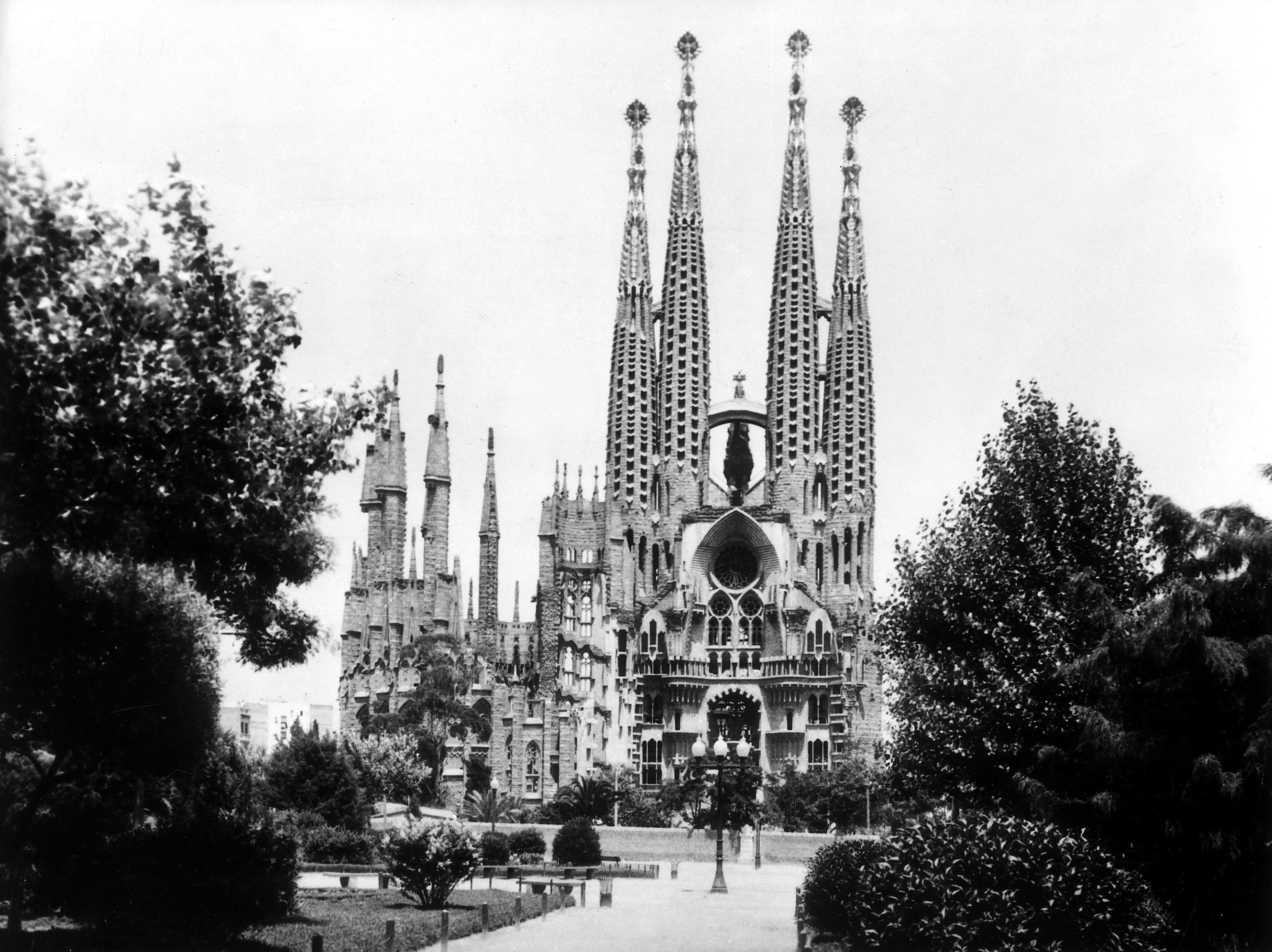 Sagrada Família basilica in Barcelona, featuring its distinct spires and ornate facade, surrounded by trees and gardens