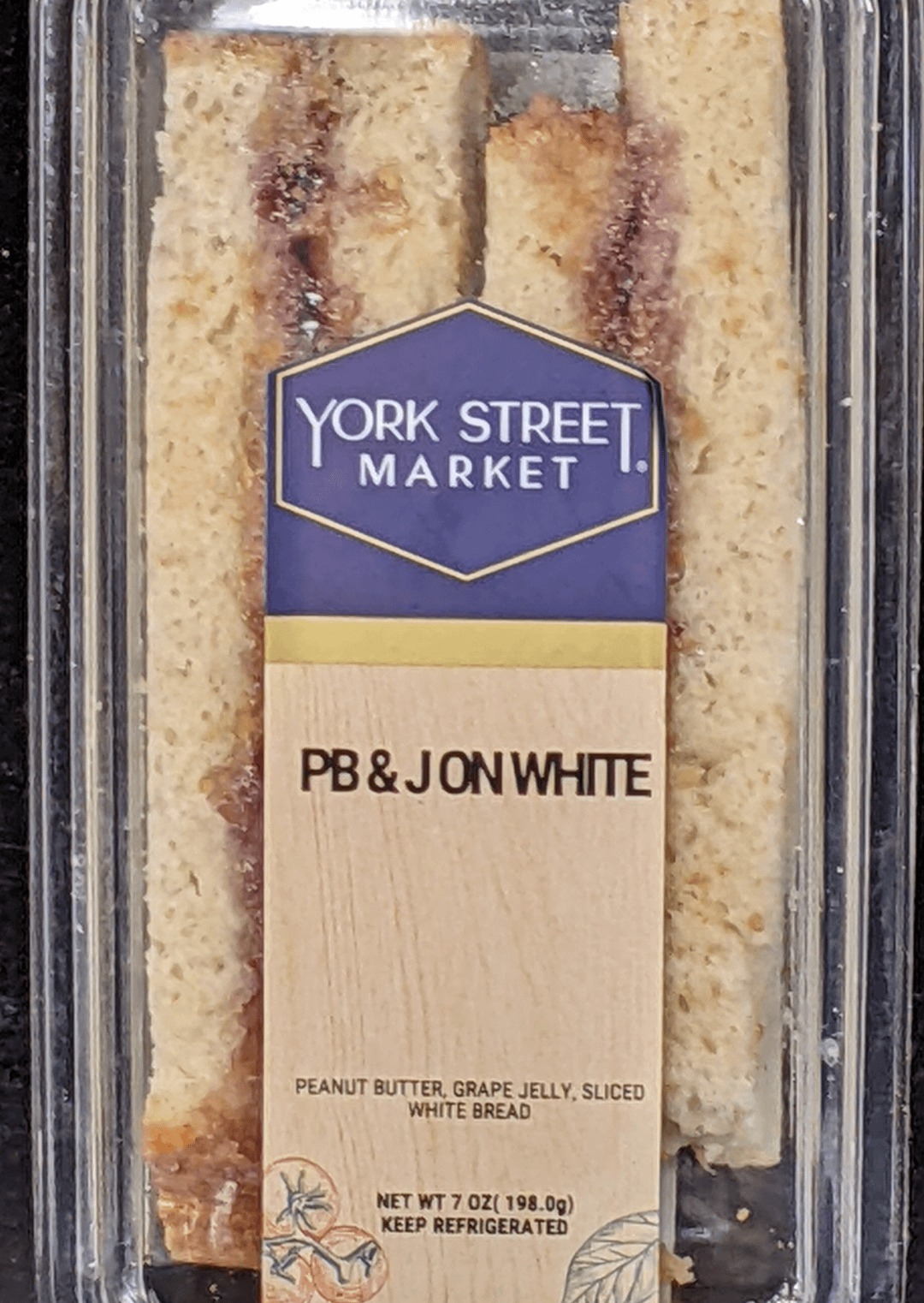 A packaged peanut butter and jelly sandwich labeled "PB&J on white" but it reads like "PB & Jon White"