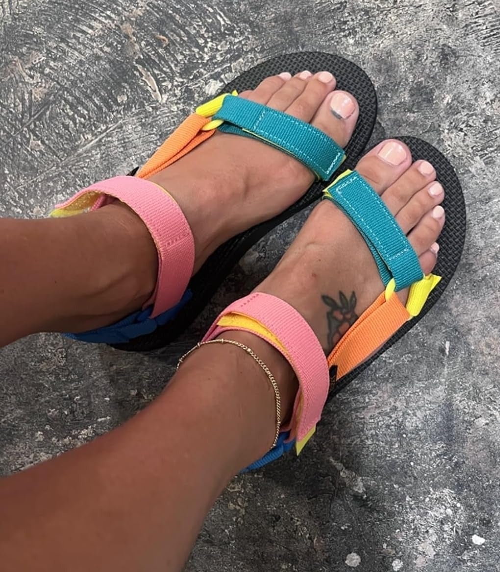 Close-up of a person wearing colorful strappy sandals, showing a tattoo on their right foot