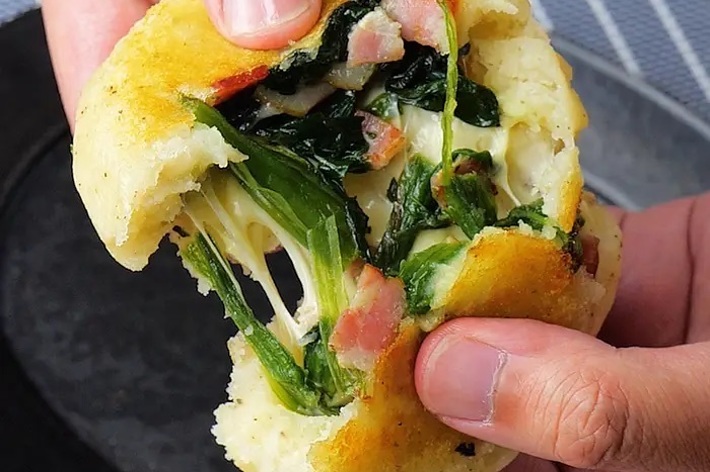 手で割られた熱々のチーズほうれん草パン。
