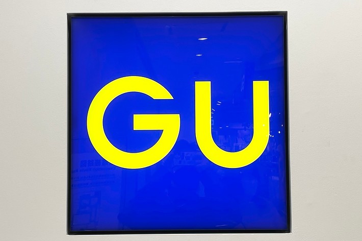 A sign featuring the letters “GU” in a bold, sans-serif font