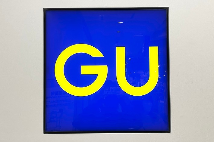 GU store sign with yellow text on a blue background