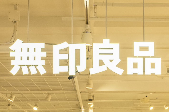 People shop and browse in a bright, well-lit Muji store, which is popular for its minimalist products. The Muji sign in Japanese is prominently displayed