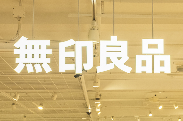 People walk through a large Muji store with several sections of household goods on display. The store&rsquo;s name is written in both Japanese and English above the entrance