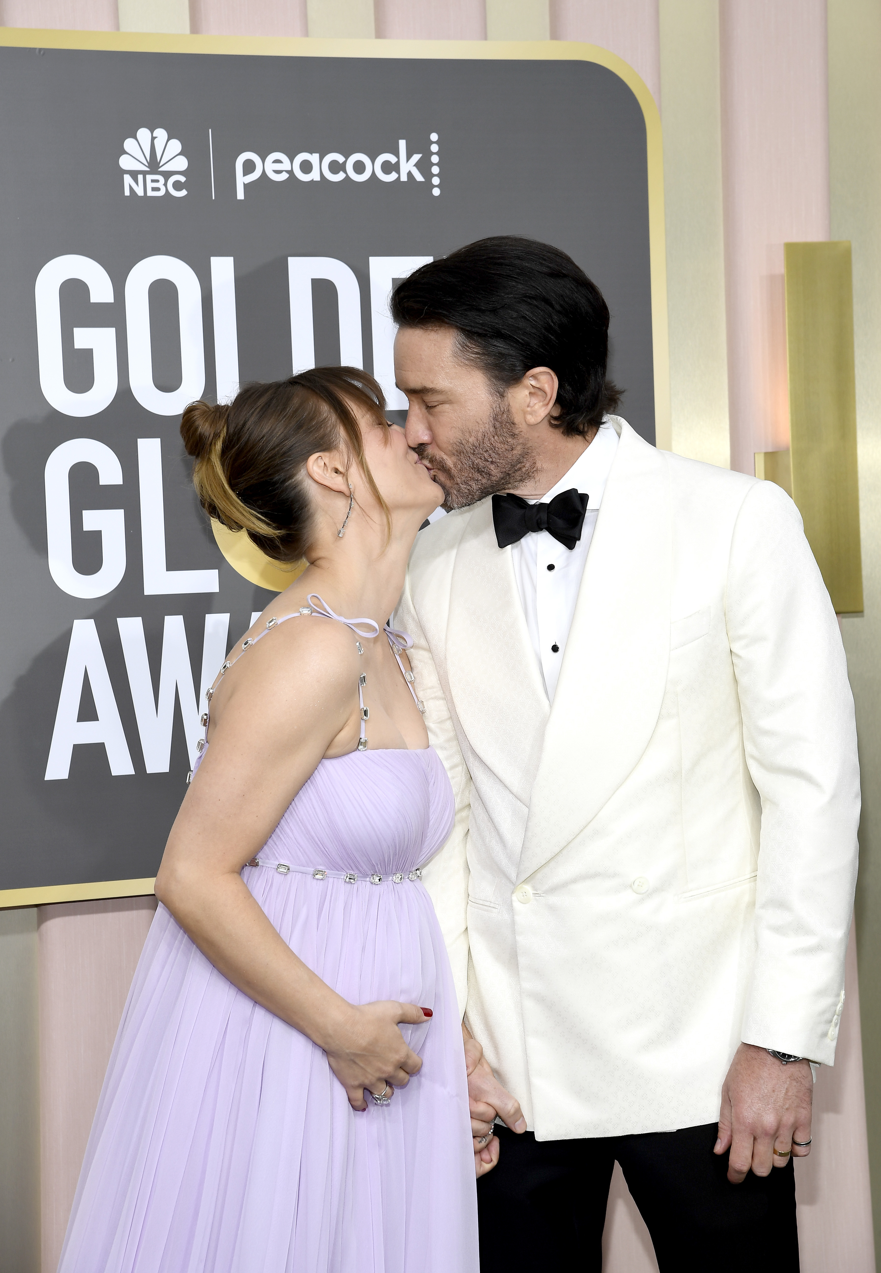 Jessica Biel, in a flowing gown, and Justin Timberlake, in a white tuxedo jacket, share a kiss on the red carpet at the Golden Globe Awards