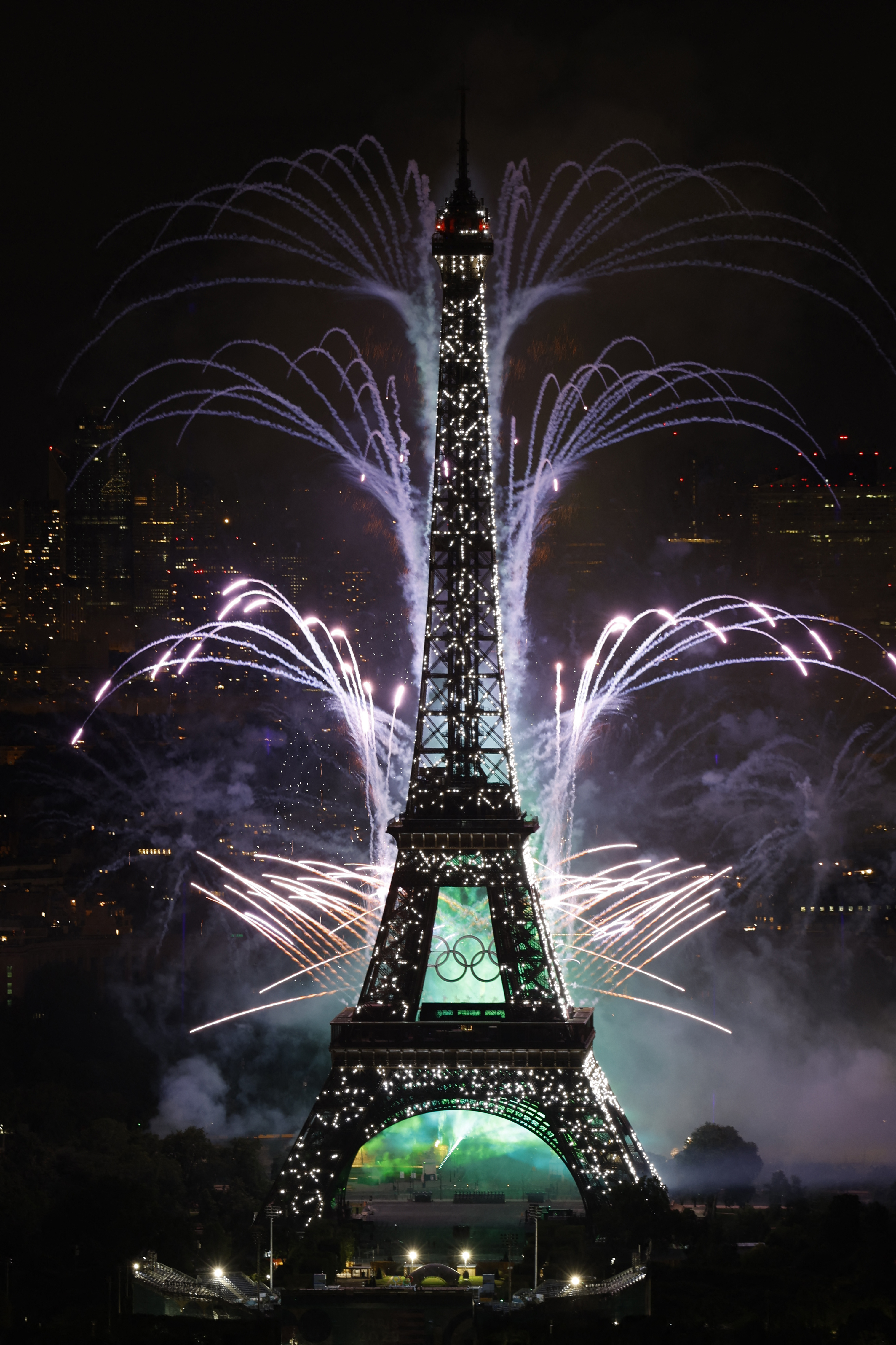 The Eiffel Tower at night with fireworks illuminating the sky in the background
