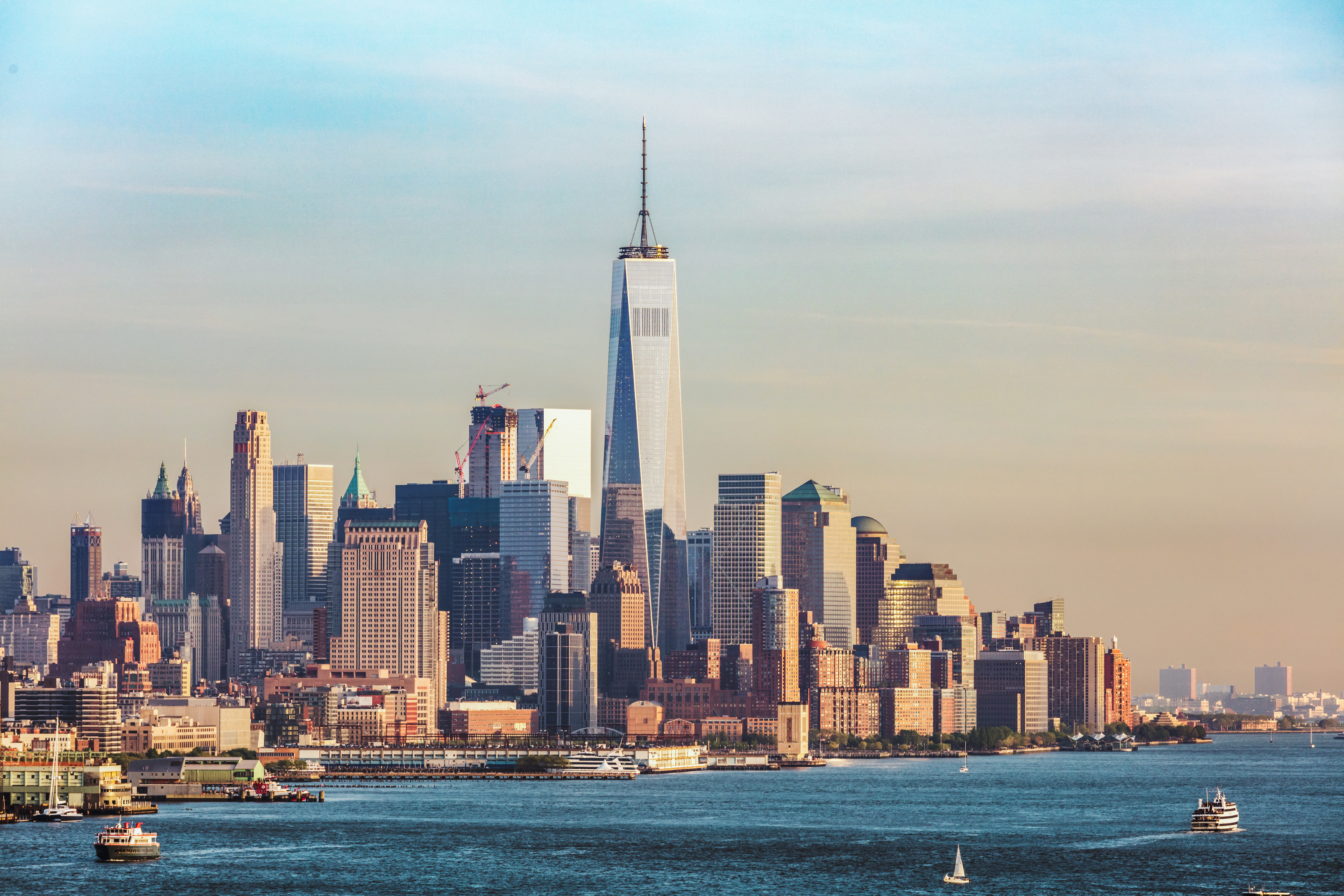 Skyline of lower Manhattan, New York City, featuring the One World Trade Center and surrounding buildings, with water in the foreground