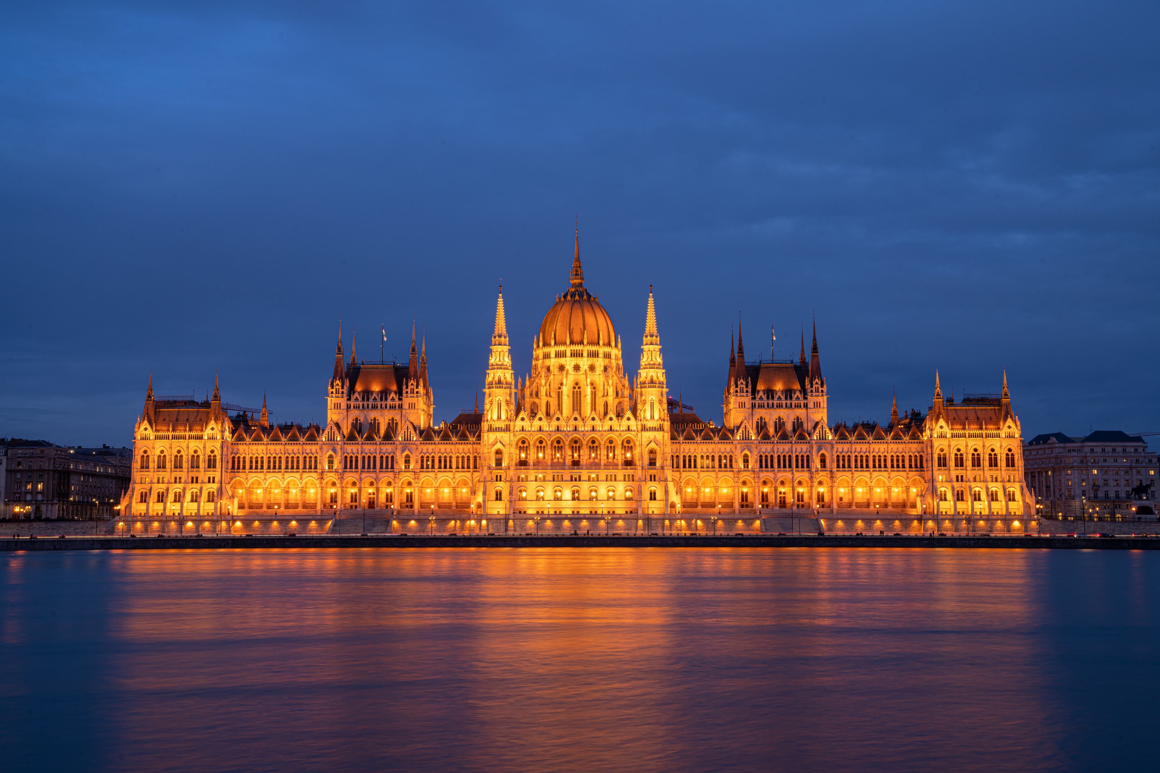 Hungarian Parliament Building illuminated at night, reflecting on the Danube River in Budapest