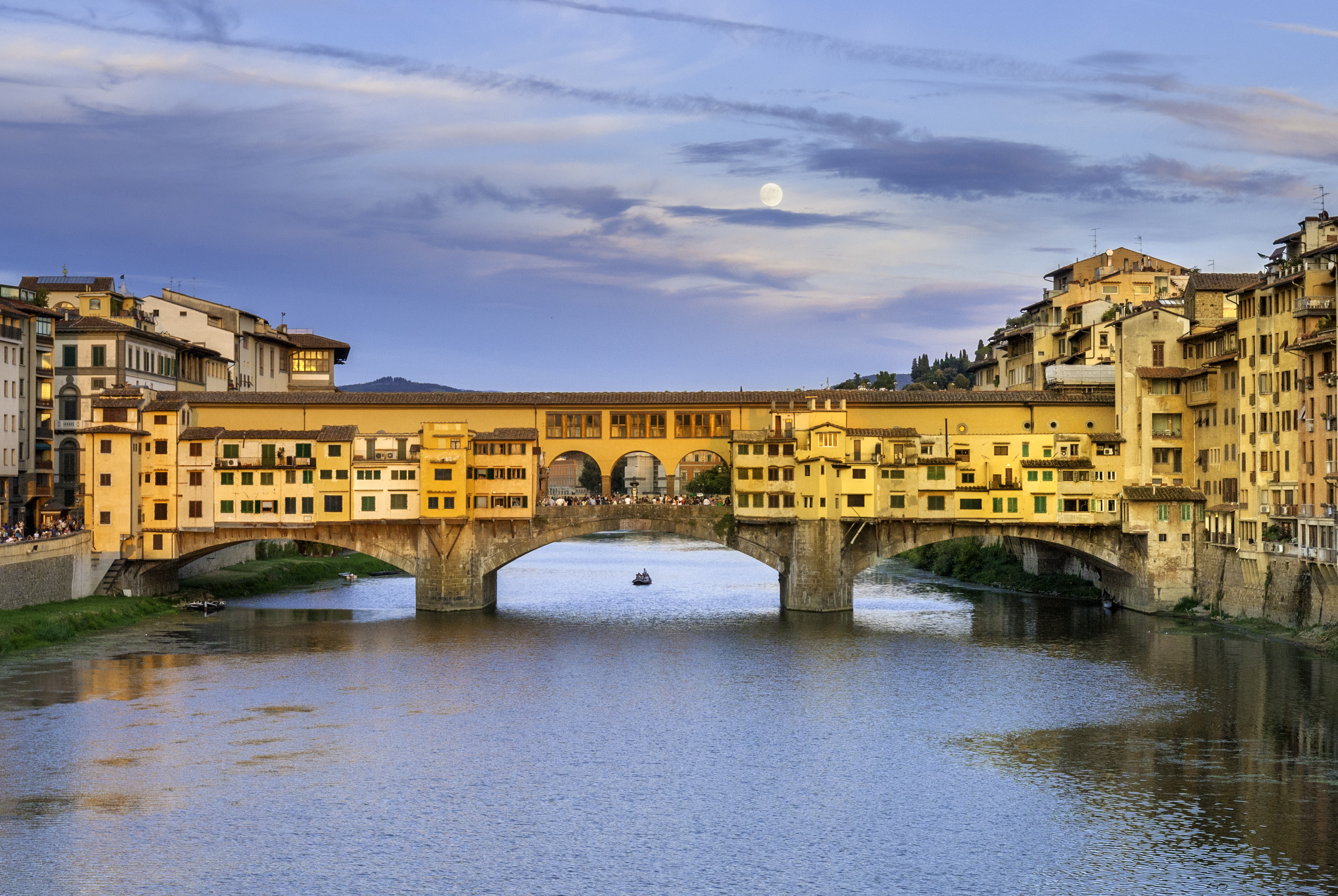 The image shows the historic Ponte Vecchio bridge spanning the Arno River in Florence, Italy, with its distinctive buildings and arches