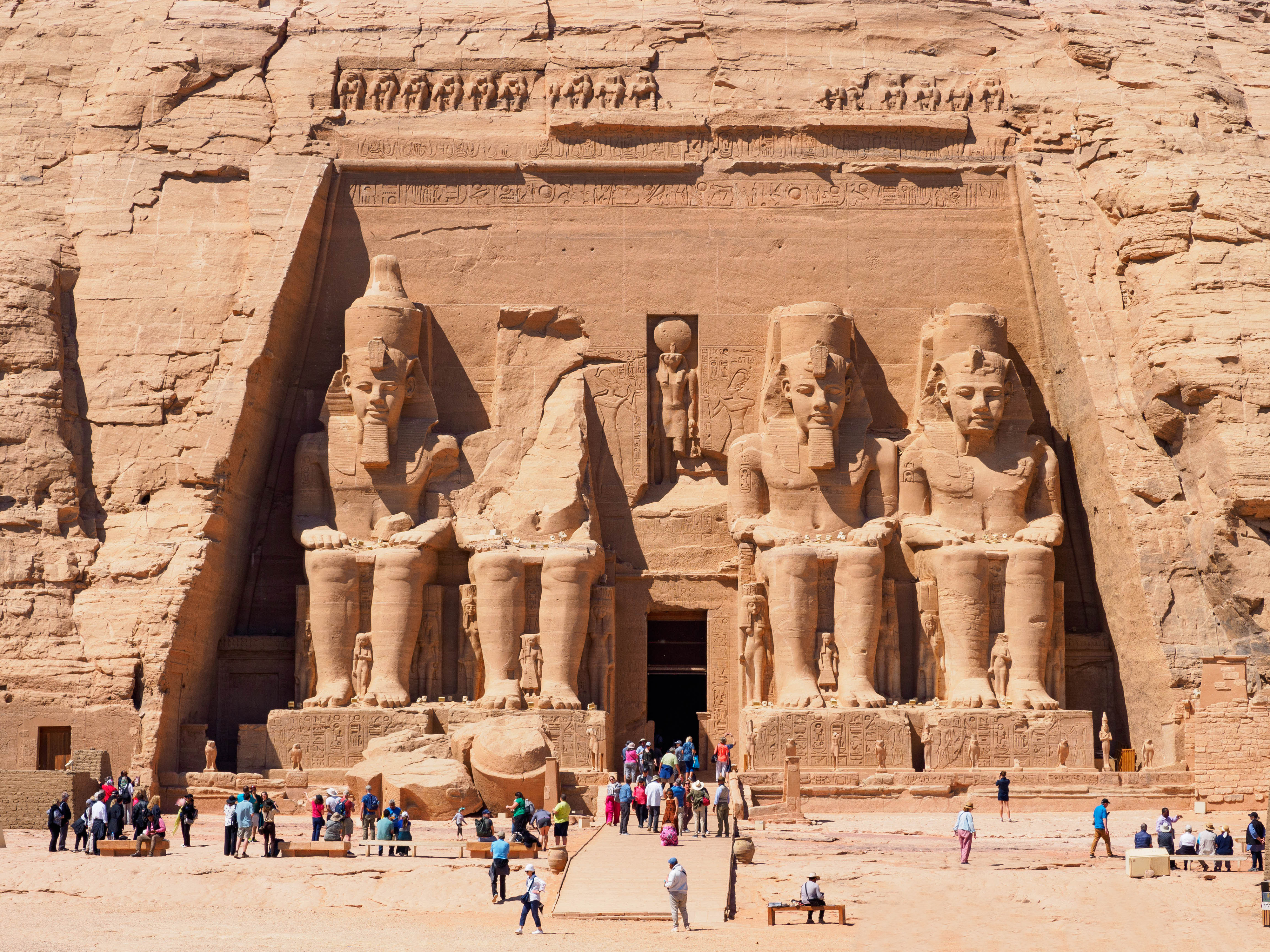 A large crowd visits the towering statues at Abu Simbel, Egypt. The ancient rock-cut temples feature four seated statues of Pharaoh Ramesses II