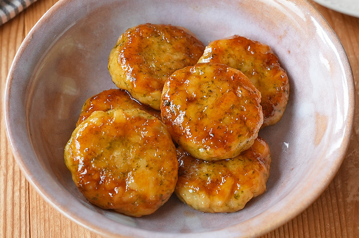 焼き鳥のつくねハンバーグが5つ入った器。背景に箸と布製のランチョンマットが見える。