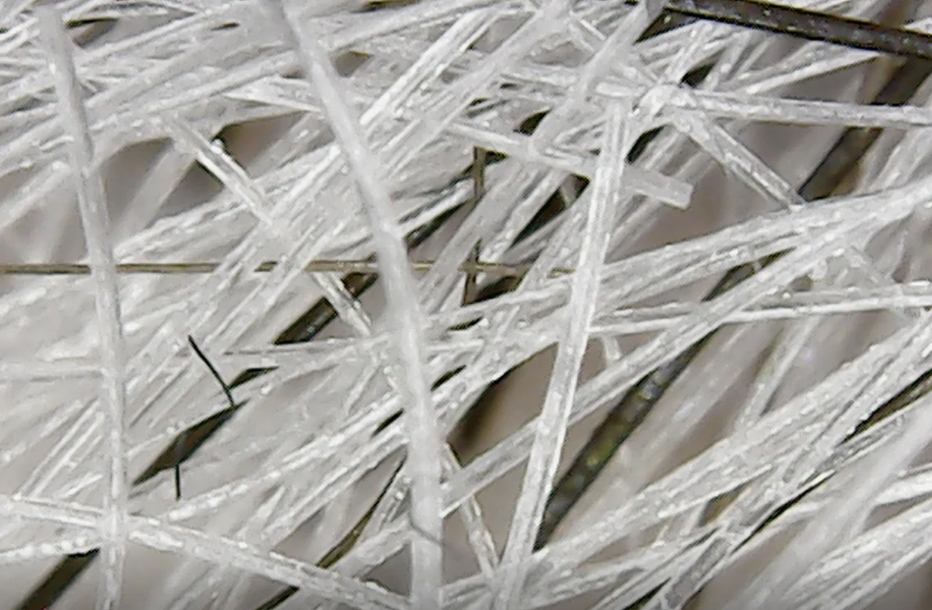 Close-up of a tangle of elongated, thin, white plastic fibers