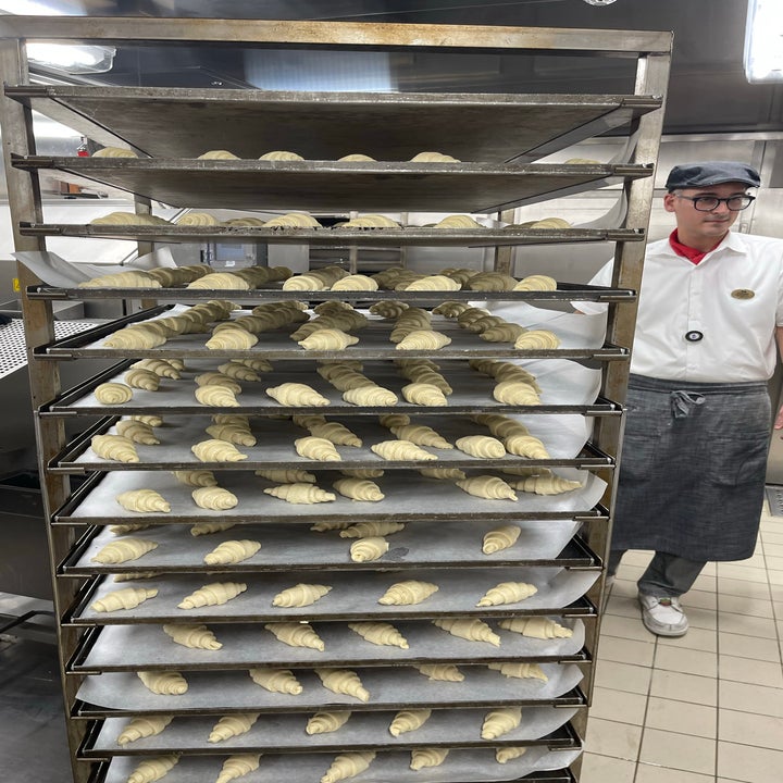 A massive baking carrier with hundreds of unbaked pastries stacked on top of each other on trays