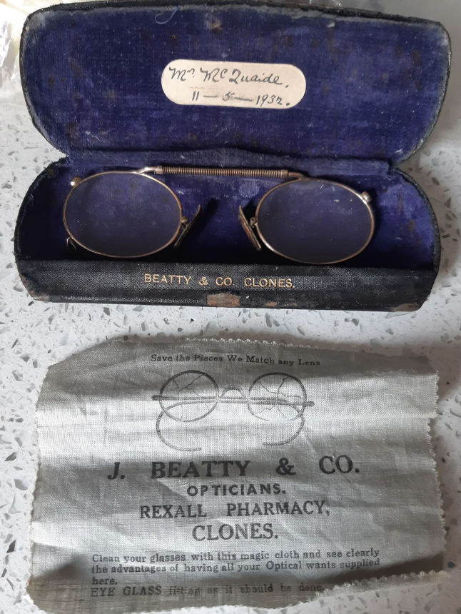 Vintage eyeglasses in a case with a label reading "Mr. W.C. Quaile, 11-5-1932" and a cloth from J. Beatty & Co. Opticians, Rexall Pharmacy, Clones