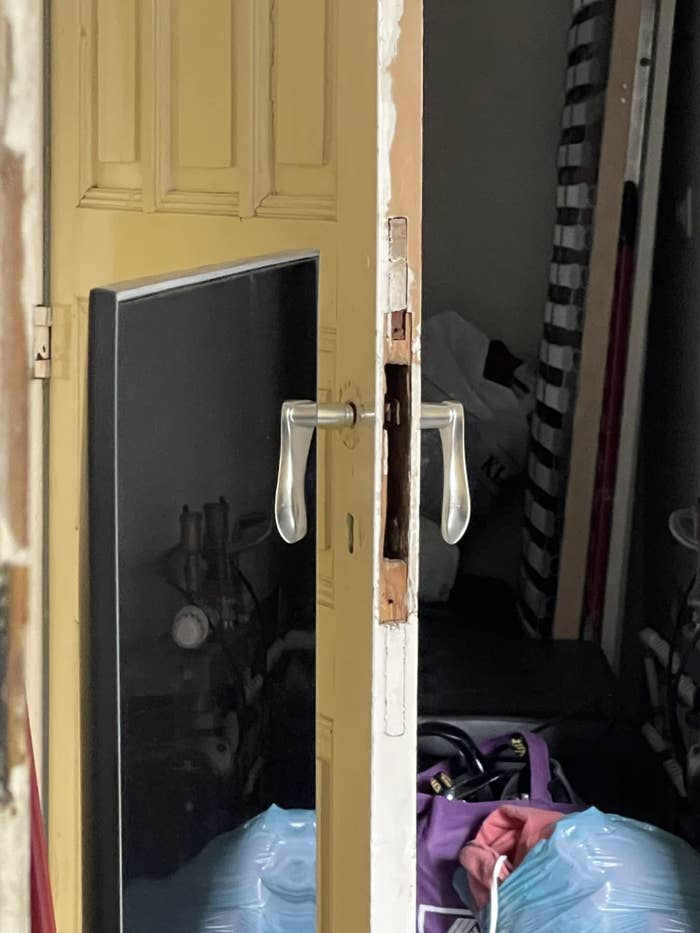 A partially open door reveals an unkempt interior space with bags and various items scattered inside