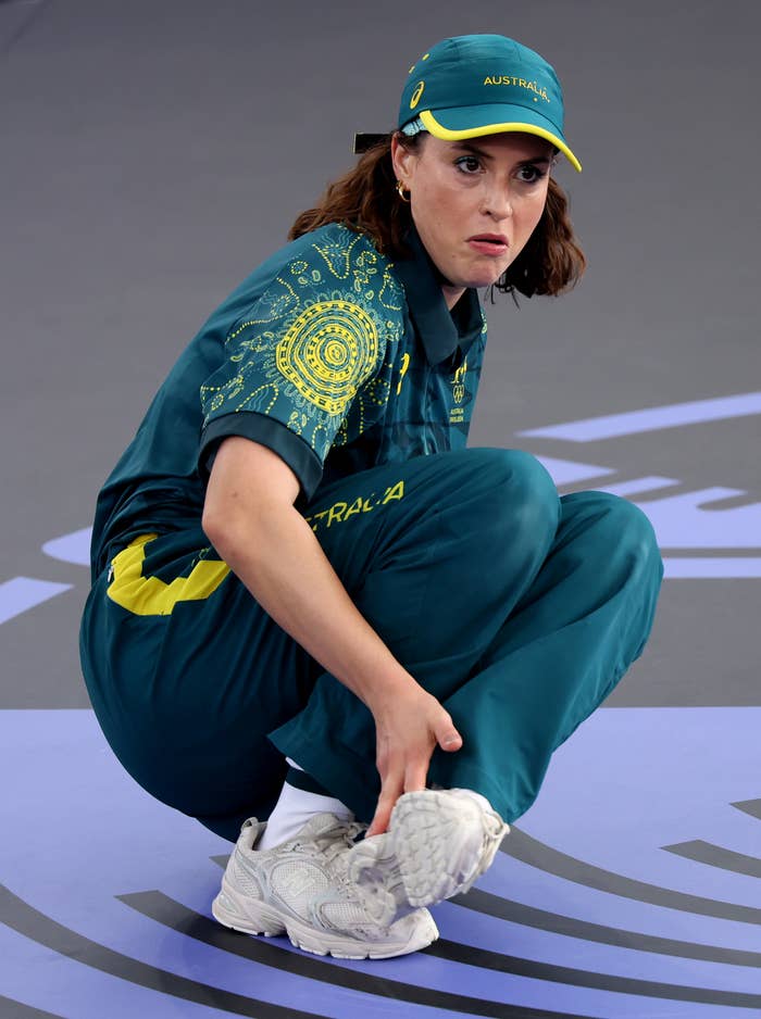 Australian breaker Rachael Gunn, dressed in team uniform, adjusts her shoe on the field