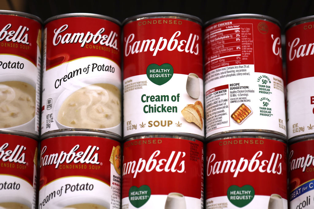Cans of Campbell’s soup, including Cream of Potato and Healthy Request Cream of Chicken, are stacked on a shelf