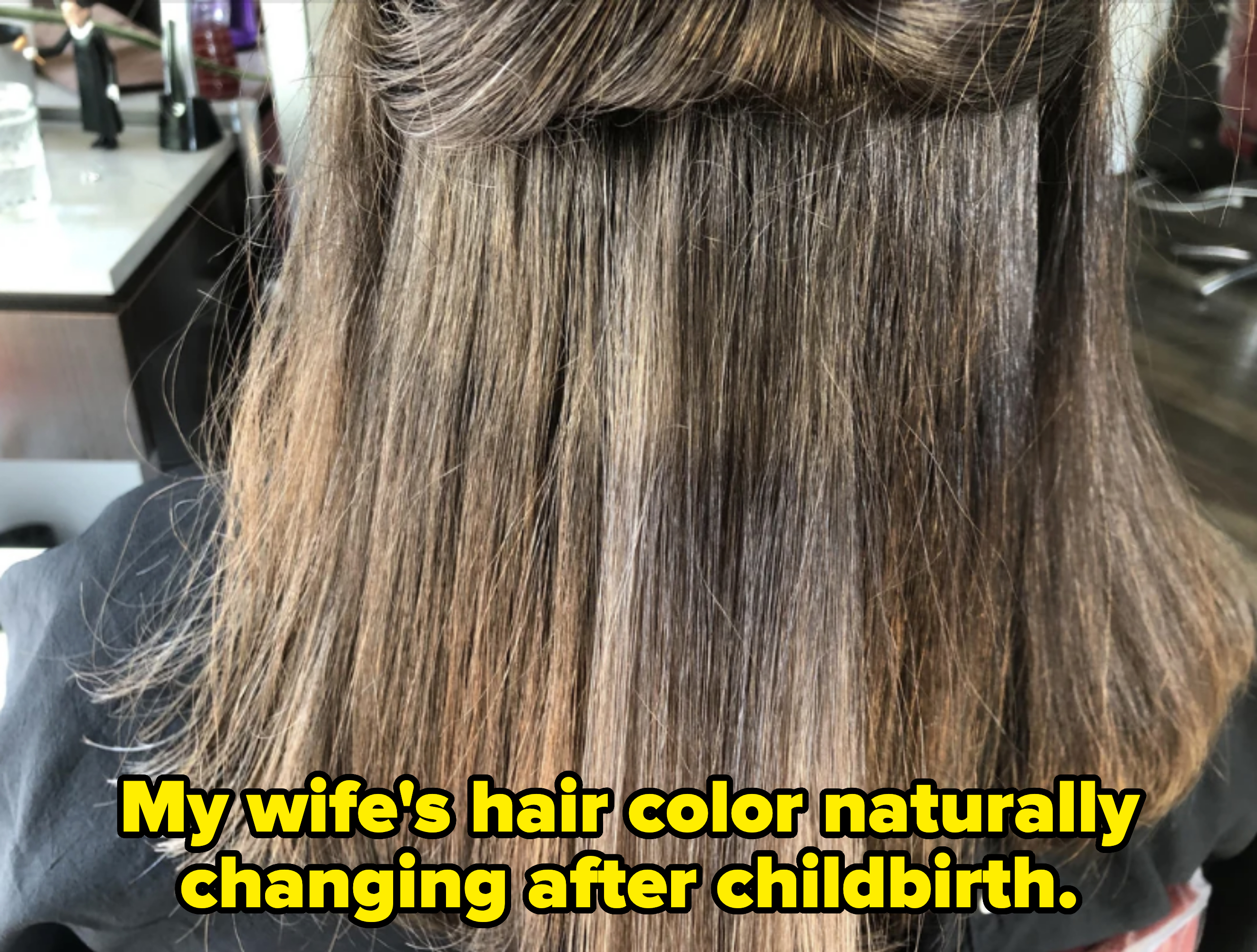 A person at a hair salon with partially straightened hair showing the progress of a hair treatment, equipment visible in the background
