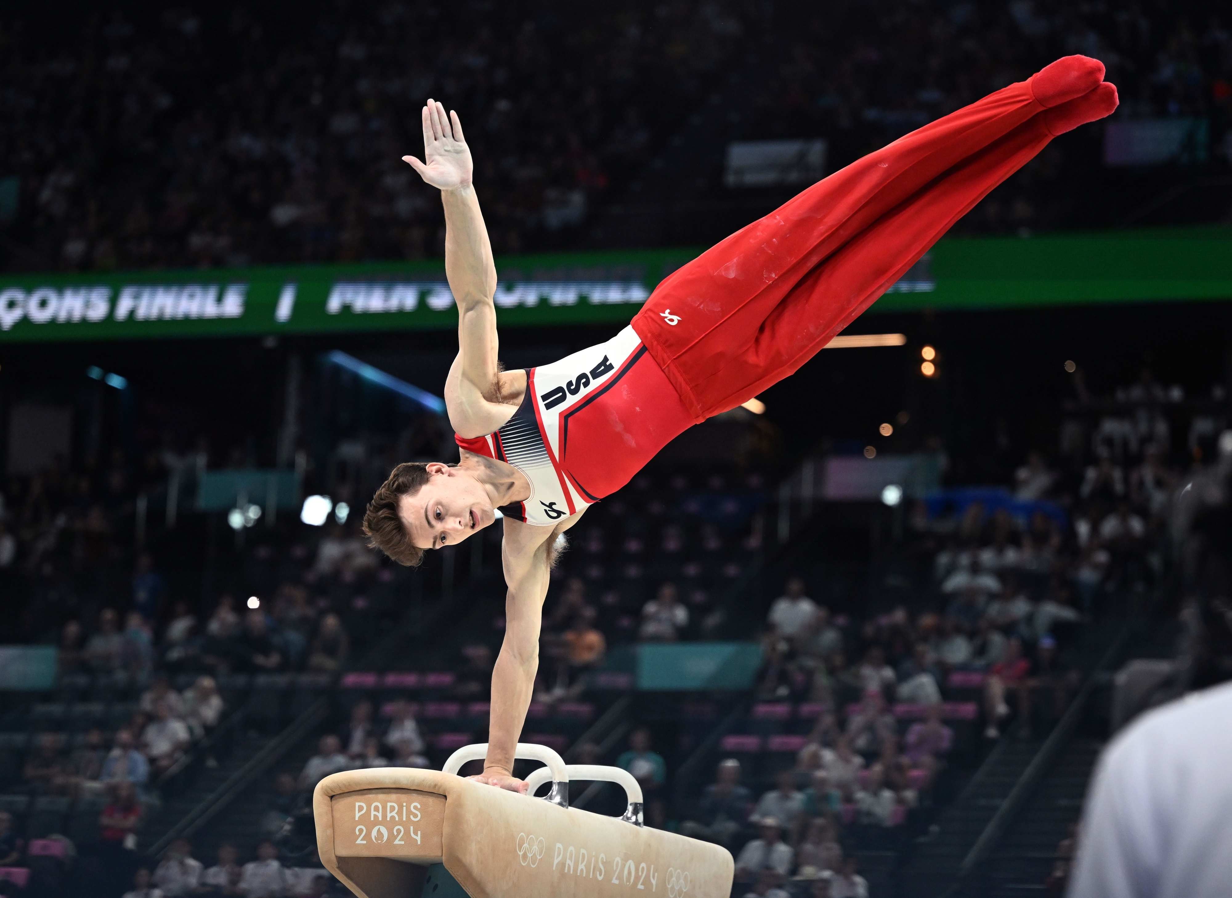 Gymnast performs on pommel horse at Paris 2024 event in front of a large crowd