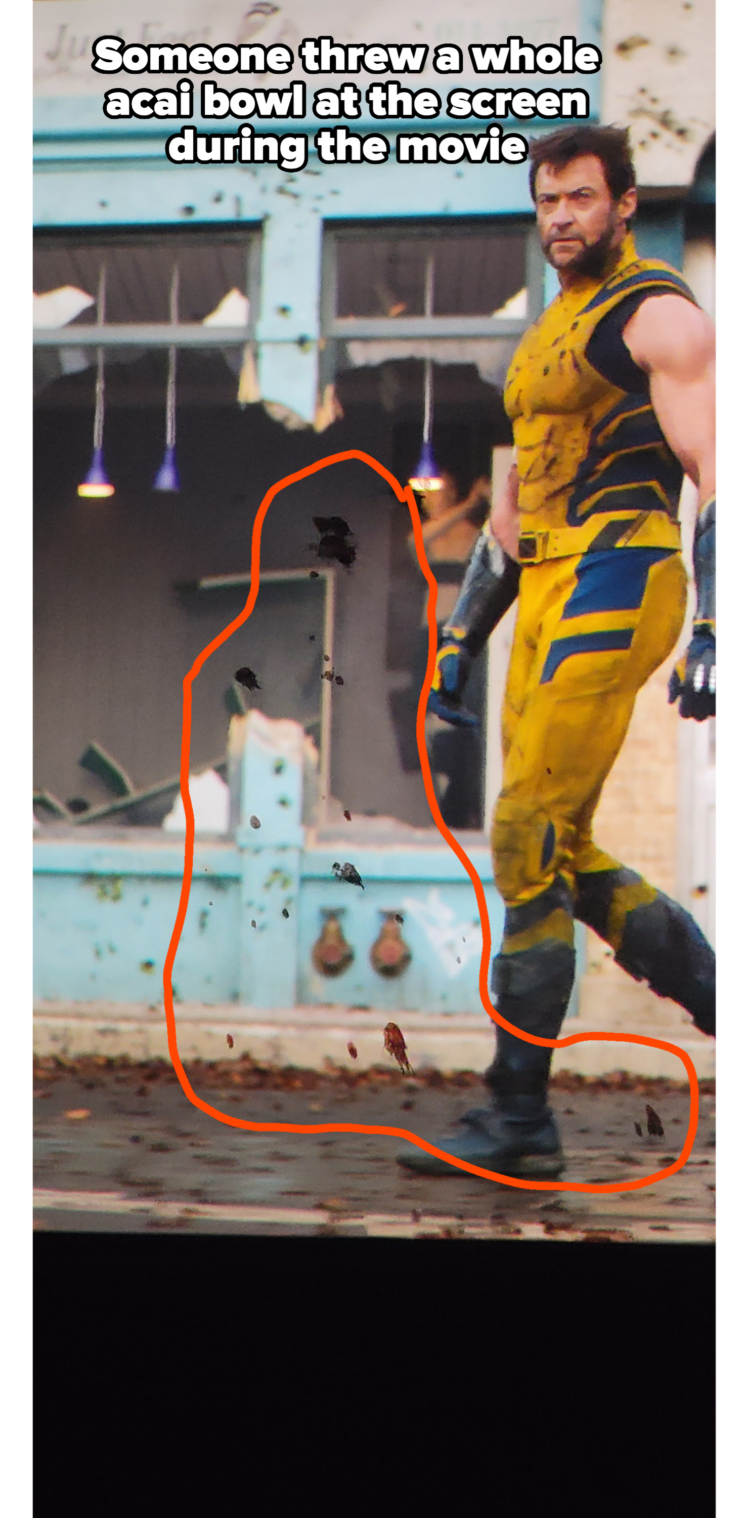 Hugh Jackman, dressed as Wolverine in a yellow and black costume, walks through a scene of debris and destruction