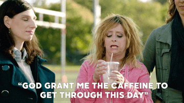 gif Three women are standing outdoors. The woman in the middle, holding a drink, is wearing a casual hoodie. The text reads, "GOD GRANT ME THE CAFFEINE TO GET THROUGH THIS DAY."
