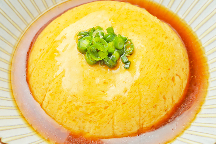 皿に盛られたふんわりとしたオムレツで、上には刻みネギが載っている。