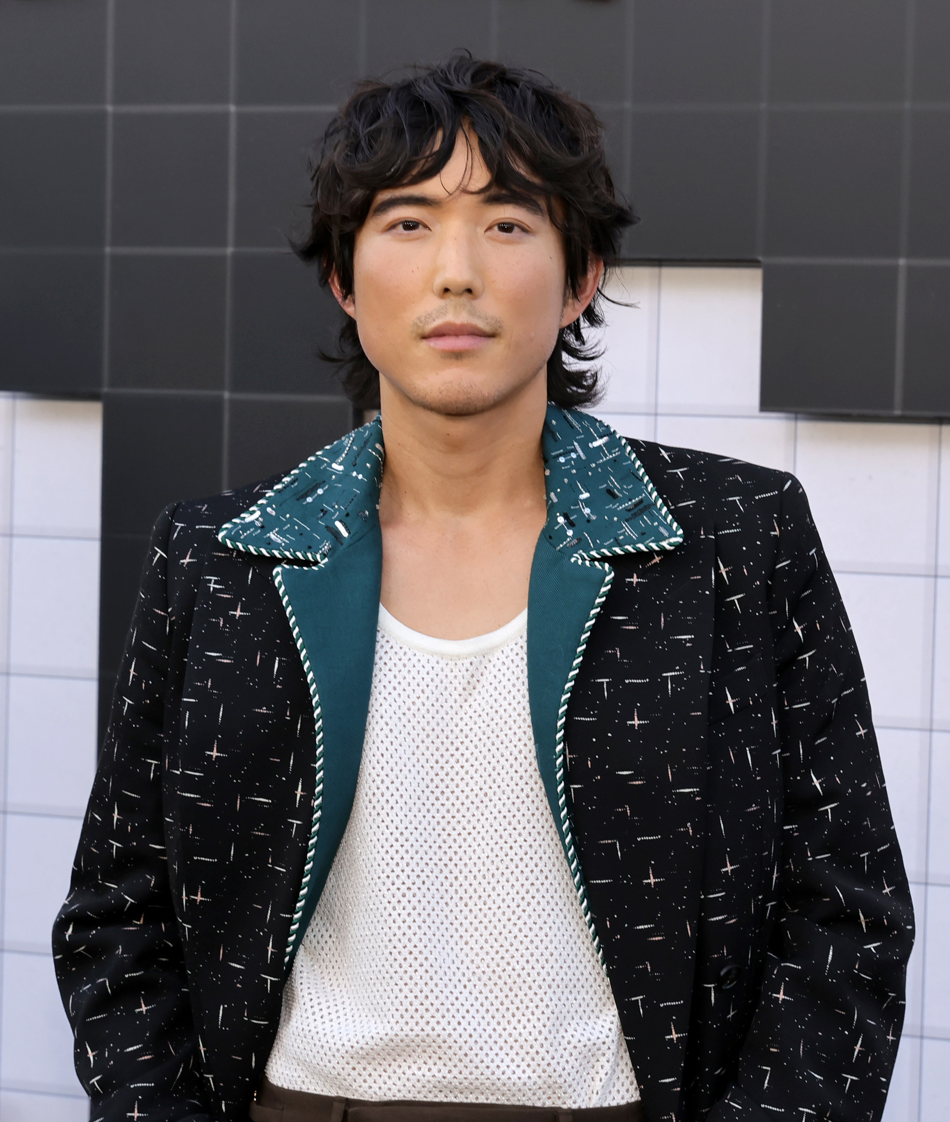 Justin H. Min wearing a patterned jacket and mesh shirt at the premiere of "The Umbrella Academy"