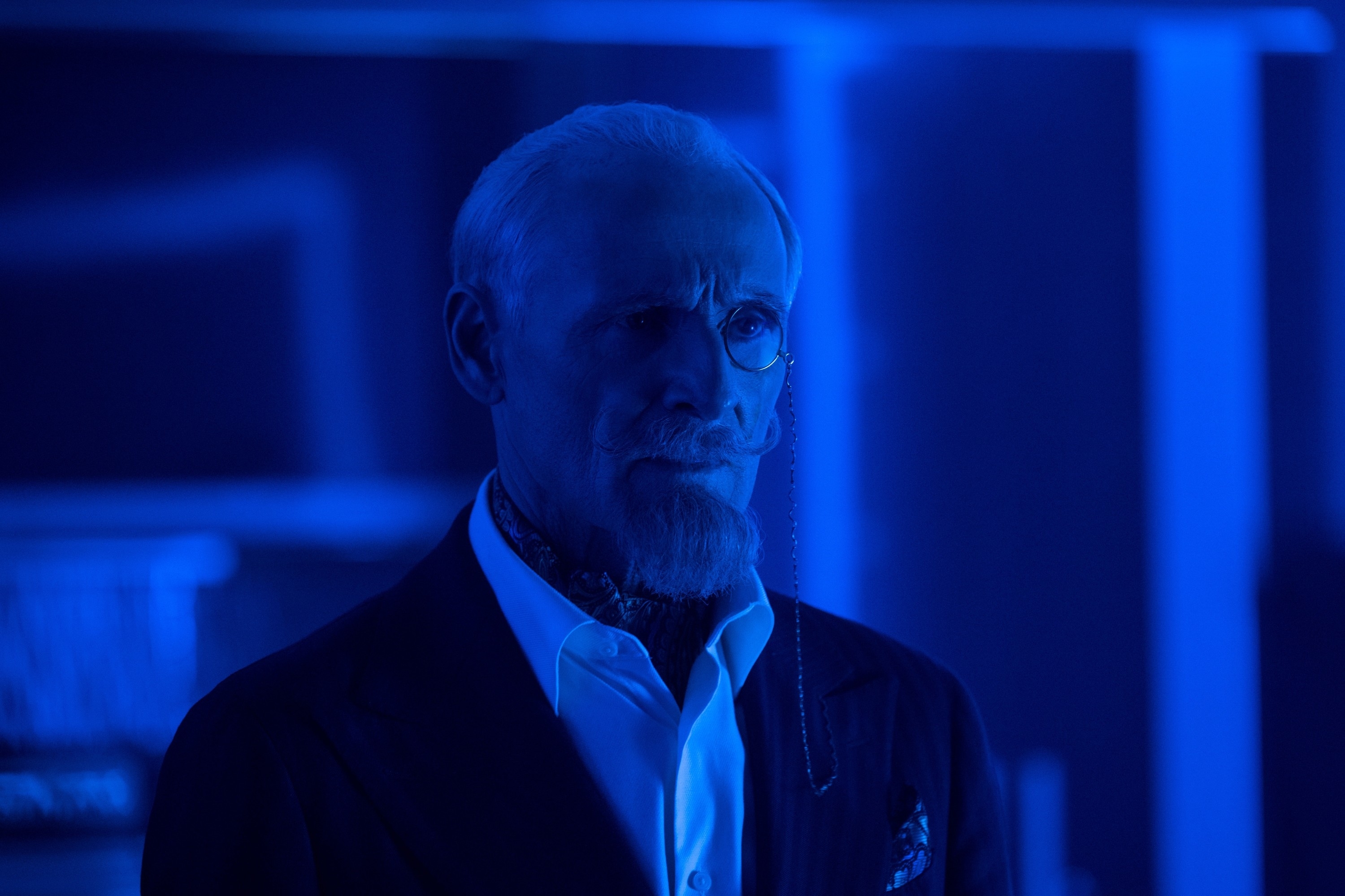 Colm Feore standing in a suit with a monocle on his eye in a scene from "The Umbrella Academy"