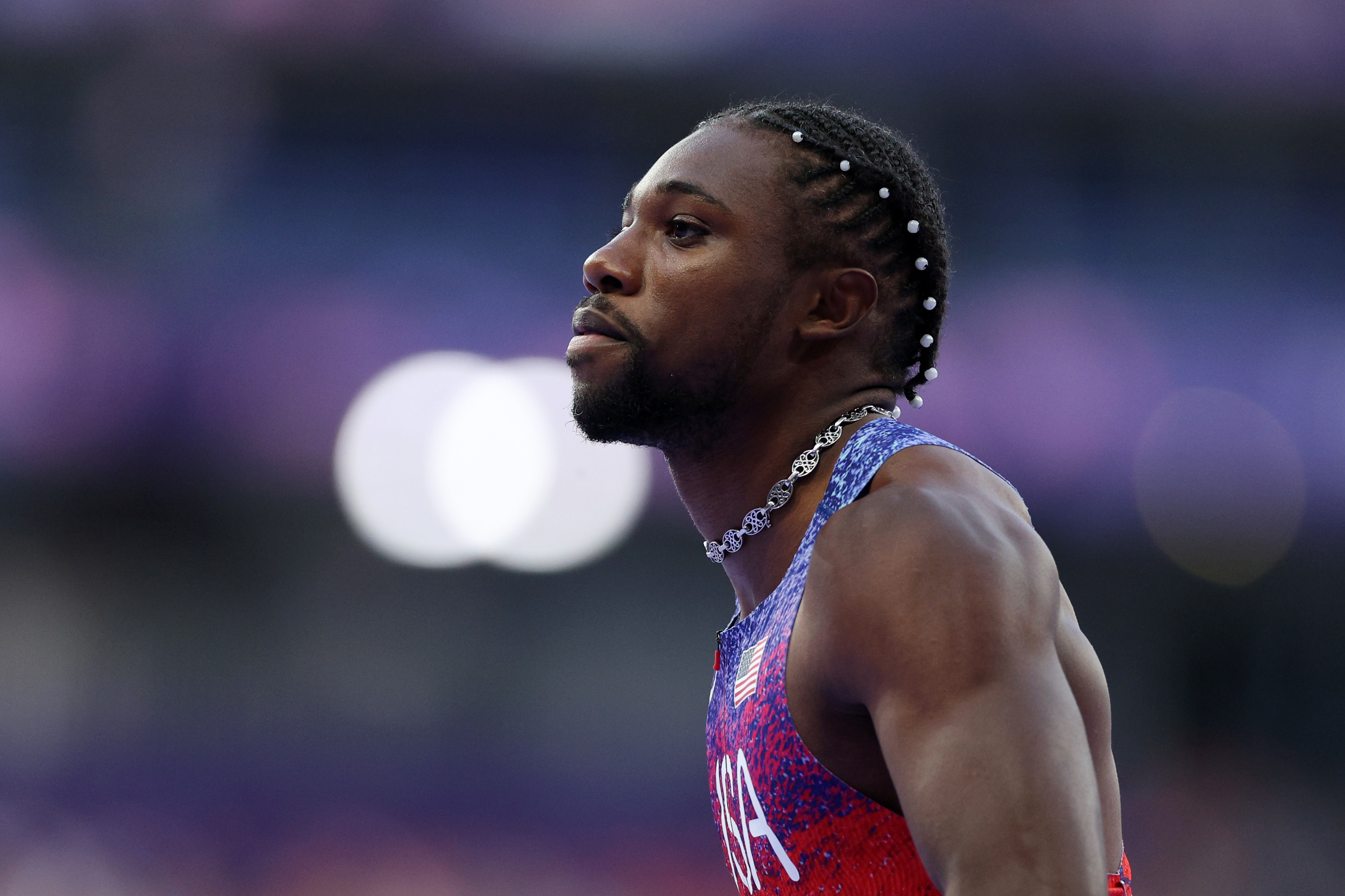 Noah Lyles looks focused in athletic gear during a track and field event.