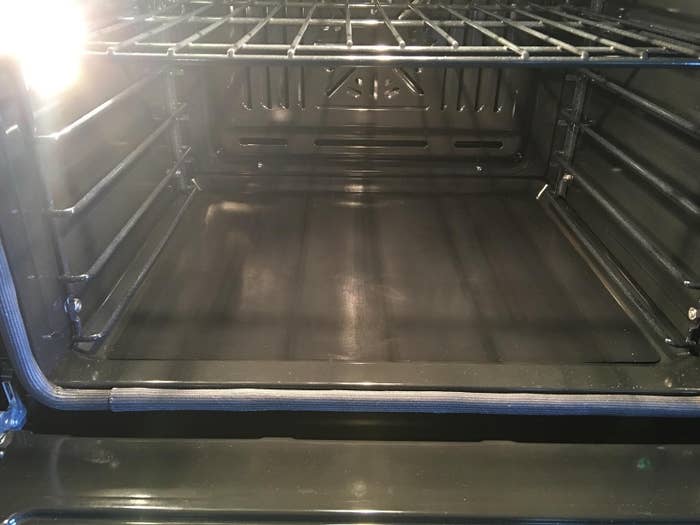 Open, empty oven with a light shining inside, showing clean interior surfaces and racks