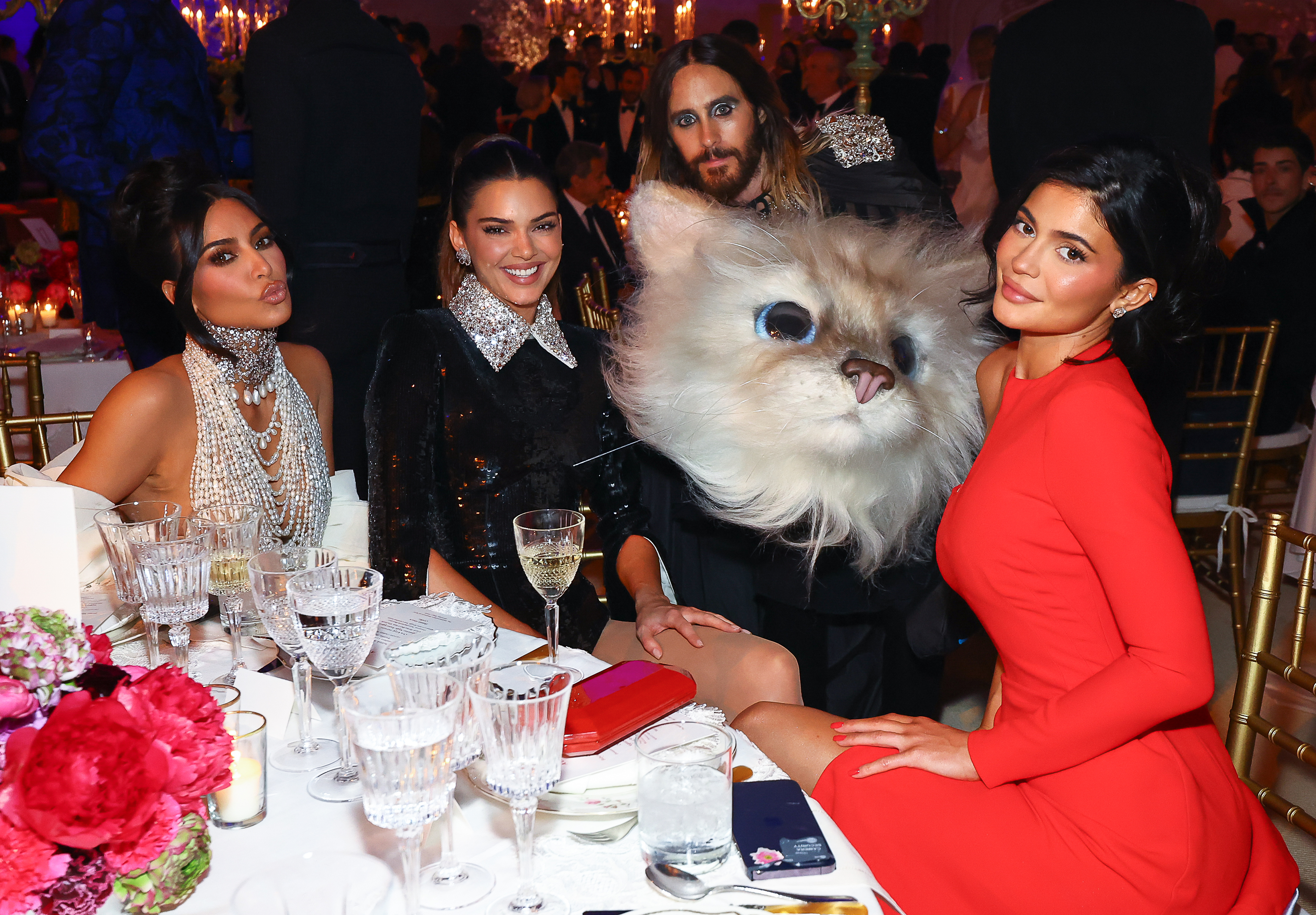 Kim Kardashian, Kendall Jenner, Jared Leto in a cat costume, and Kylie Jenner seated at a formal event table