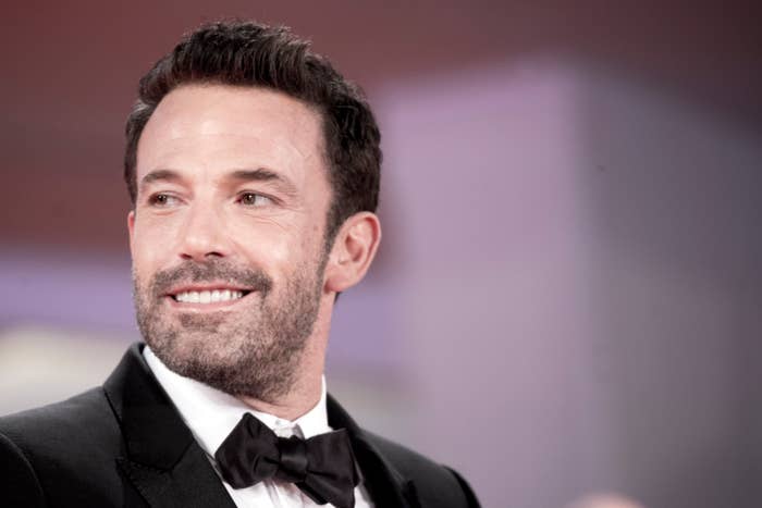 Ben Affleck smiles while wearing a formal black suit and bow tie at a public event