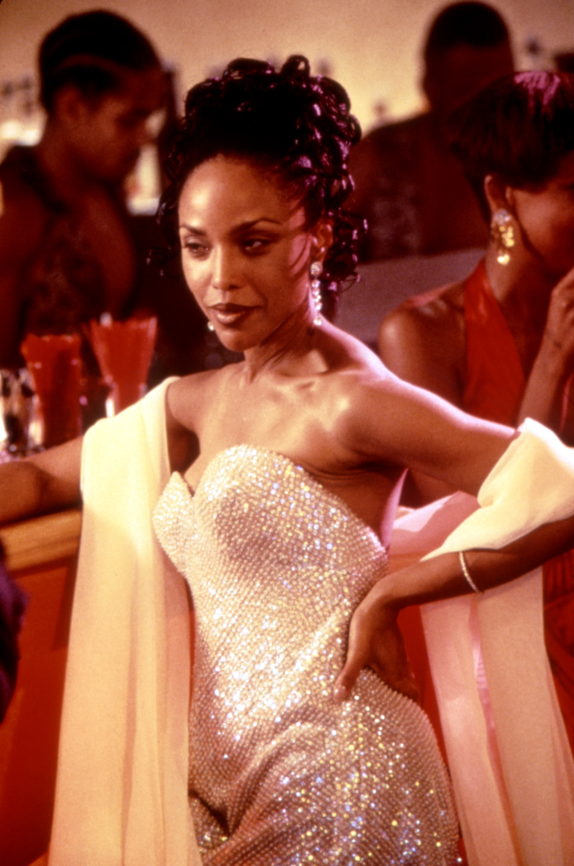 Jada Pinkett Smith in an elegant strapless, sparkly gown and shawl at an event, standing with hand on hip and people in the background