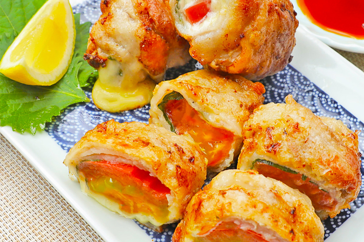 皿に盛られた肉巻き野菜とれんげに入った赤いソース。