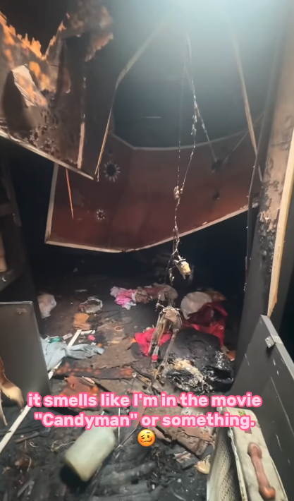 Burned room with soot-covered walls and ceiling, debris on the floor, and hanging objects. Caption reads: "it smells like I'm in the movie 'Candyman' or something."