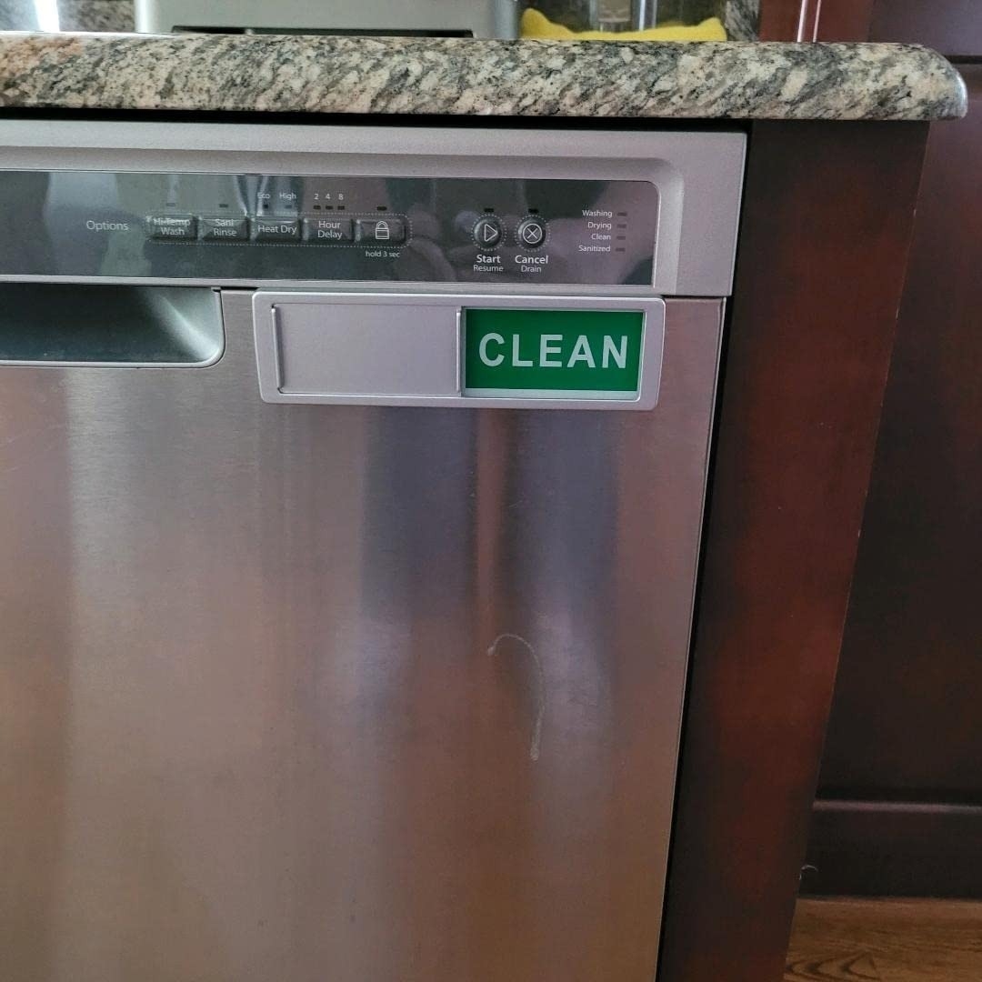 Stainless steel dishwasher with a &quot;CLEAN&quot; sign indicating that the dishes inside are clean