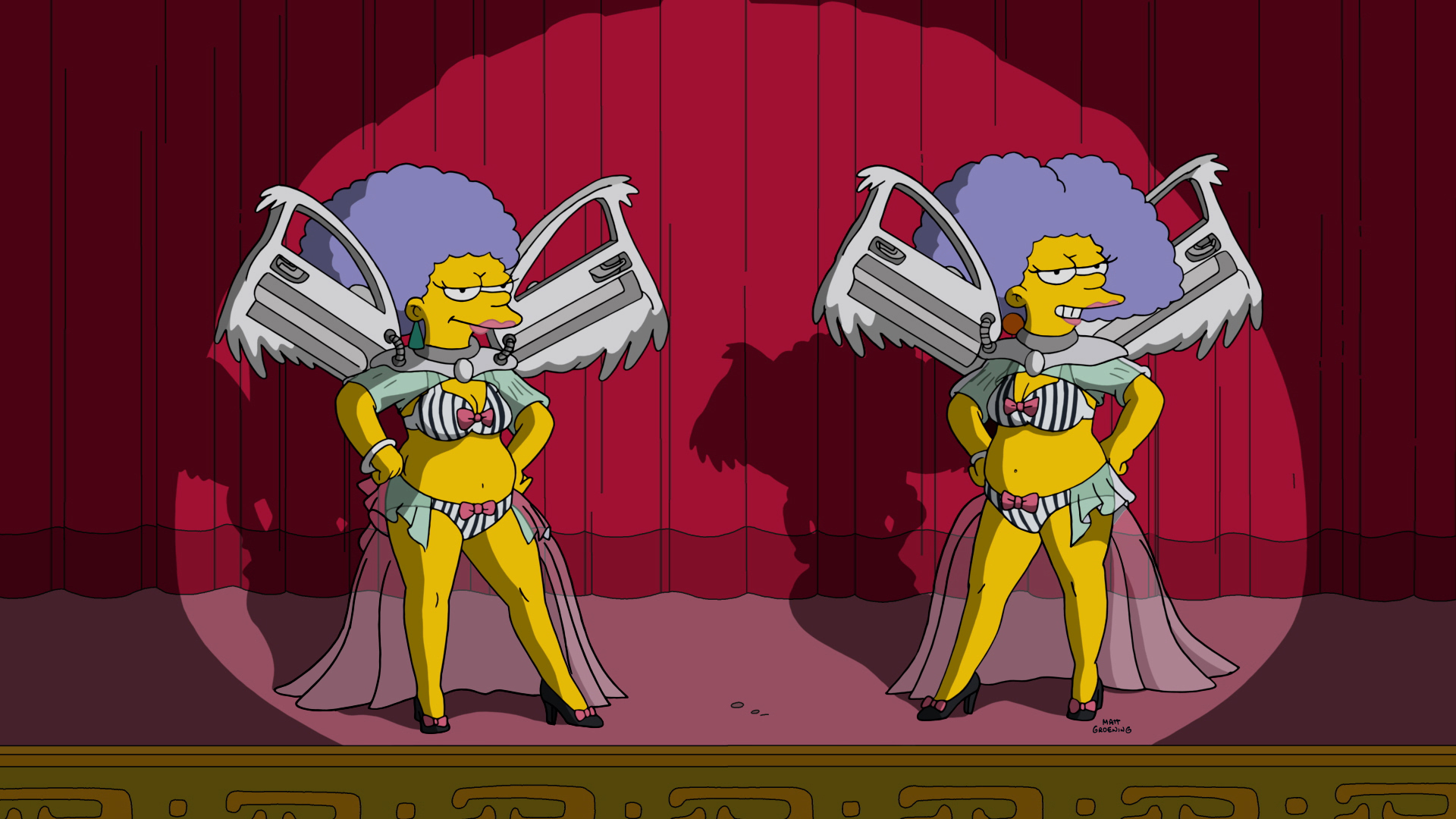 Marge Simpson and Selma Bouvier from The Simpsons wearing winged costumes and standing on stage in front of a red curtain