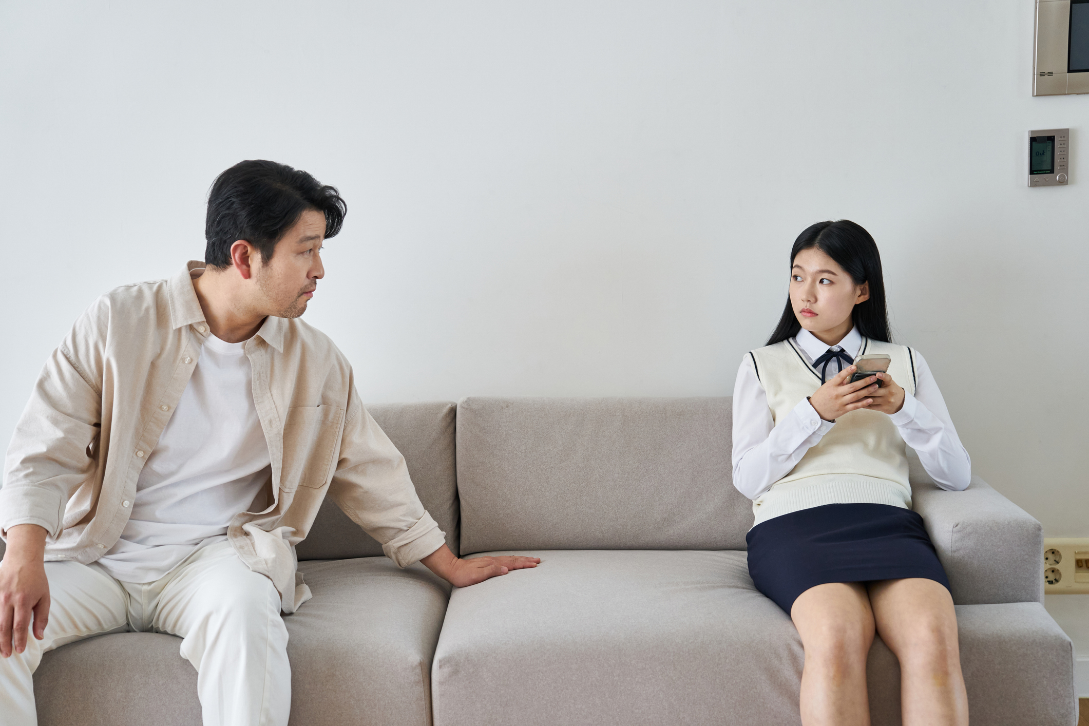 男性と女性がソファに座っています。男性はカジュアルな服装で、女性は制服を着ています。