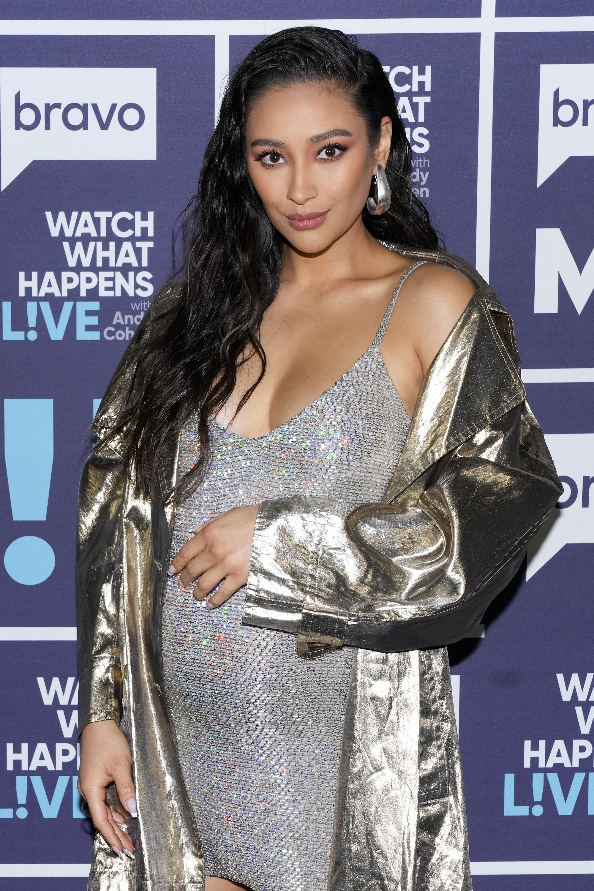 Shay Mitchell poses on the Watch What Happens Live! red carpet, wearing a shimmering dress and a metallic jacket