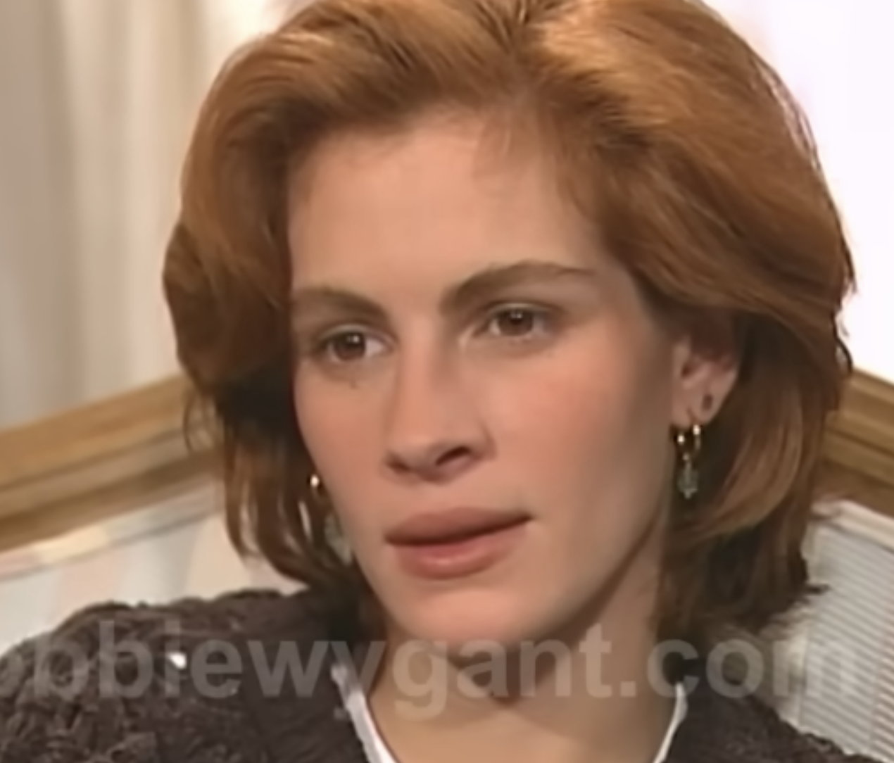 Julia Roberts in a close-up interview shot, wearing a knitted sweater and hoop earrings