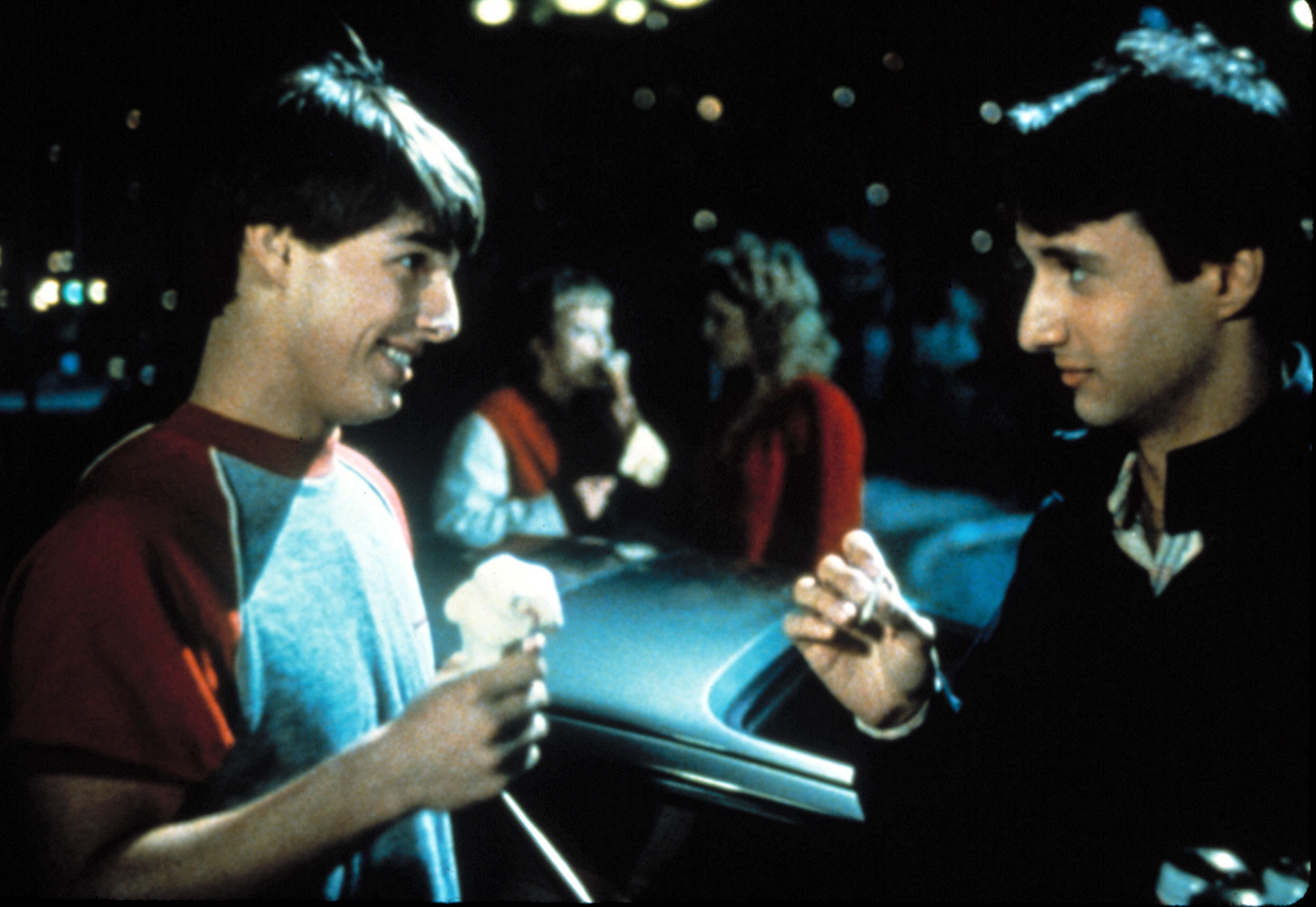 Tom Cruise and Bronson Pinchot in a scene from the movie "Risky Business," talking to each other while holding ice cream and a cigarette