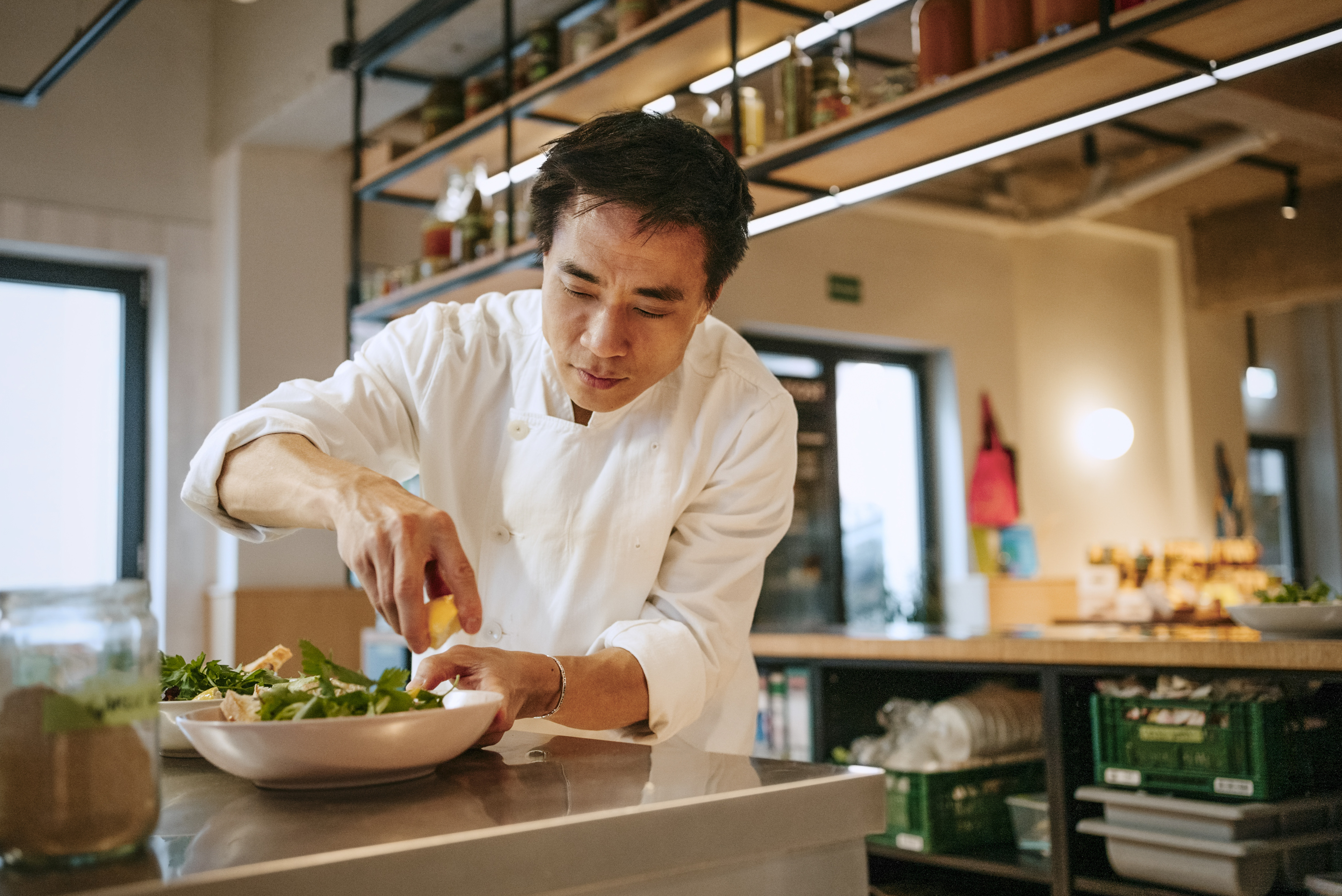 A chef meticulously garnishes a dish with a lemon in a modern kitchen