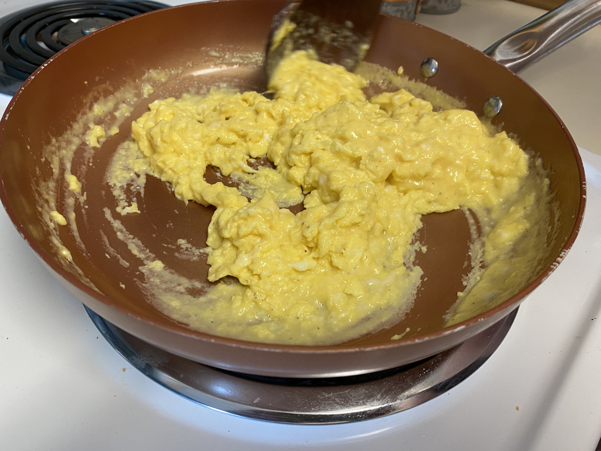 Scrambled eggs being cooked in a nonstick pan on a stovetop