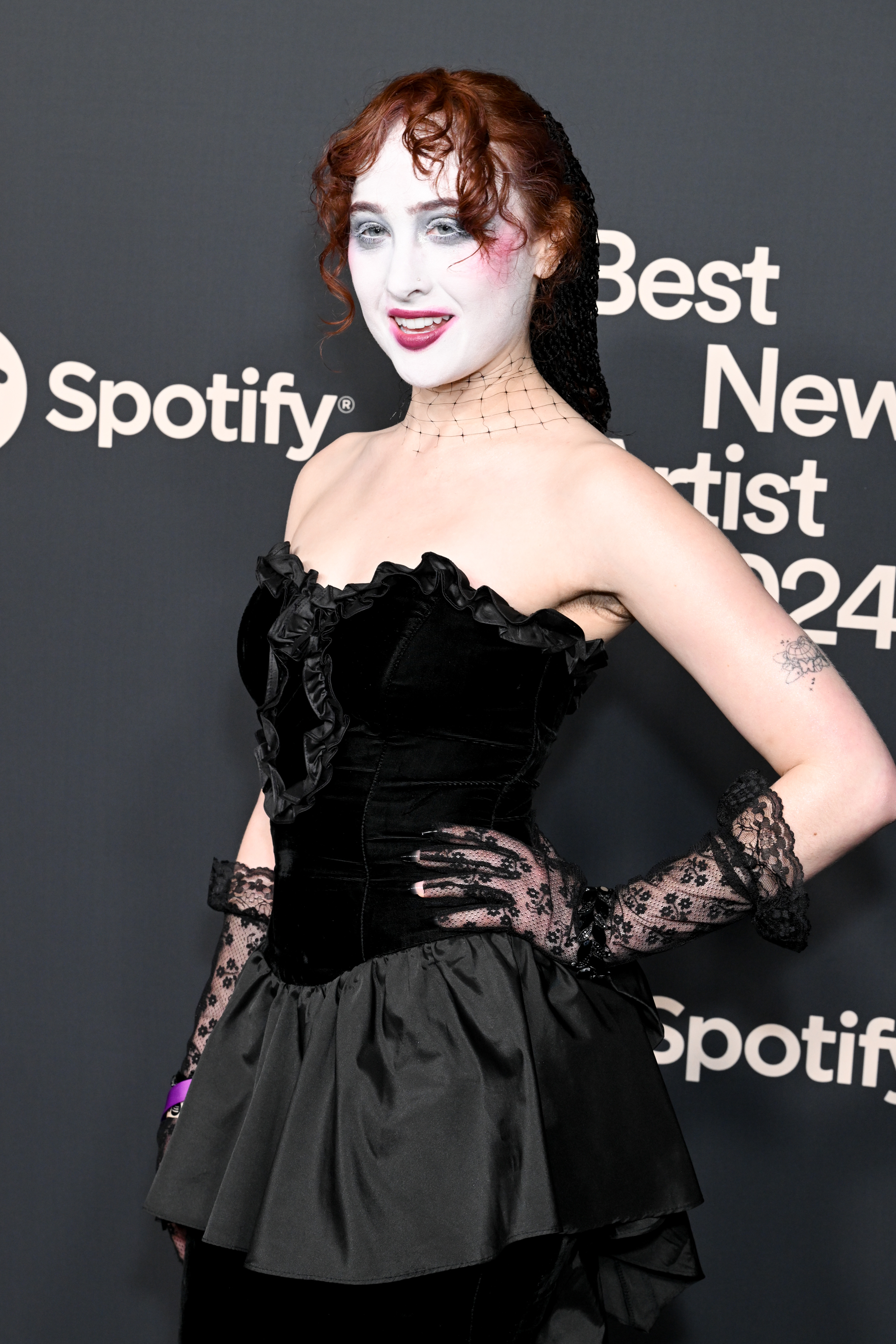 Chappell Roan on the red carpet wearing a gothic-inspired black velvet dress, lace gloves, and dramatic makeup, attending Spotify's Best New Artist 2024 event