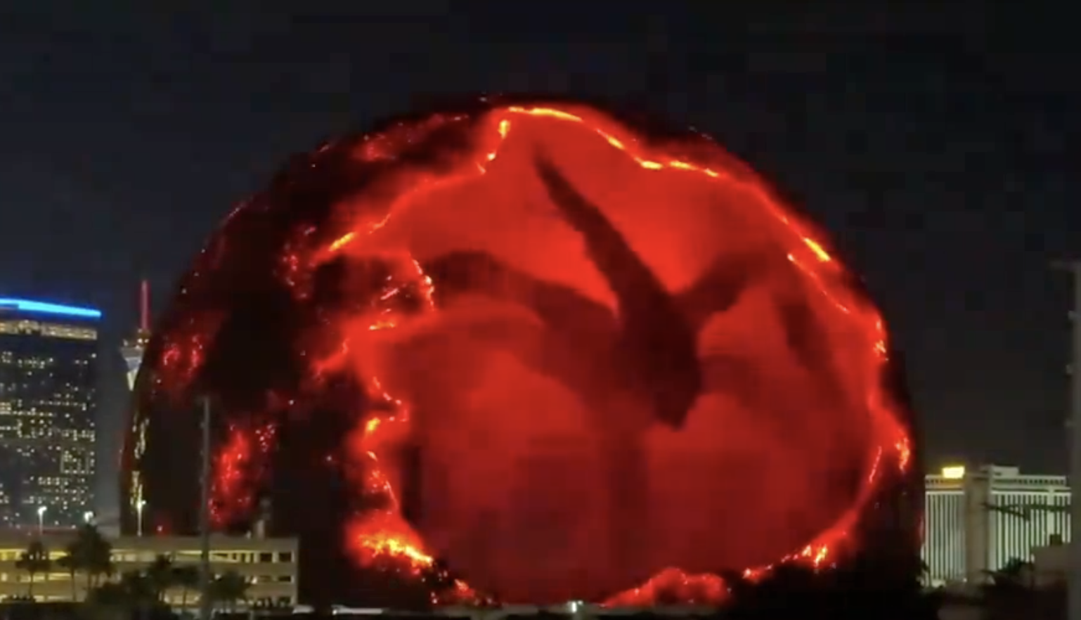 Las Vegas Sphere with a massive dragon projection, resembling fire and lava, against the city skyline at night