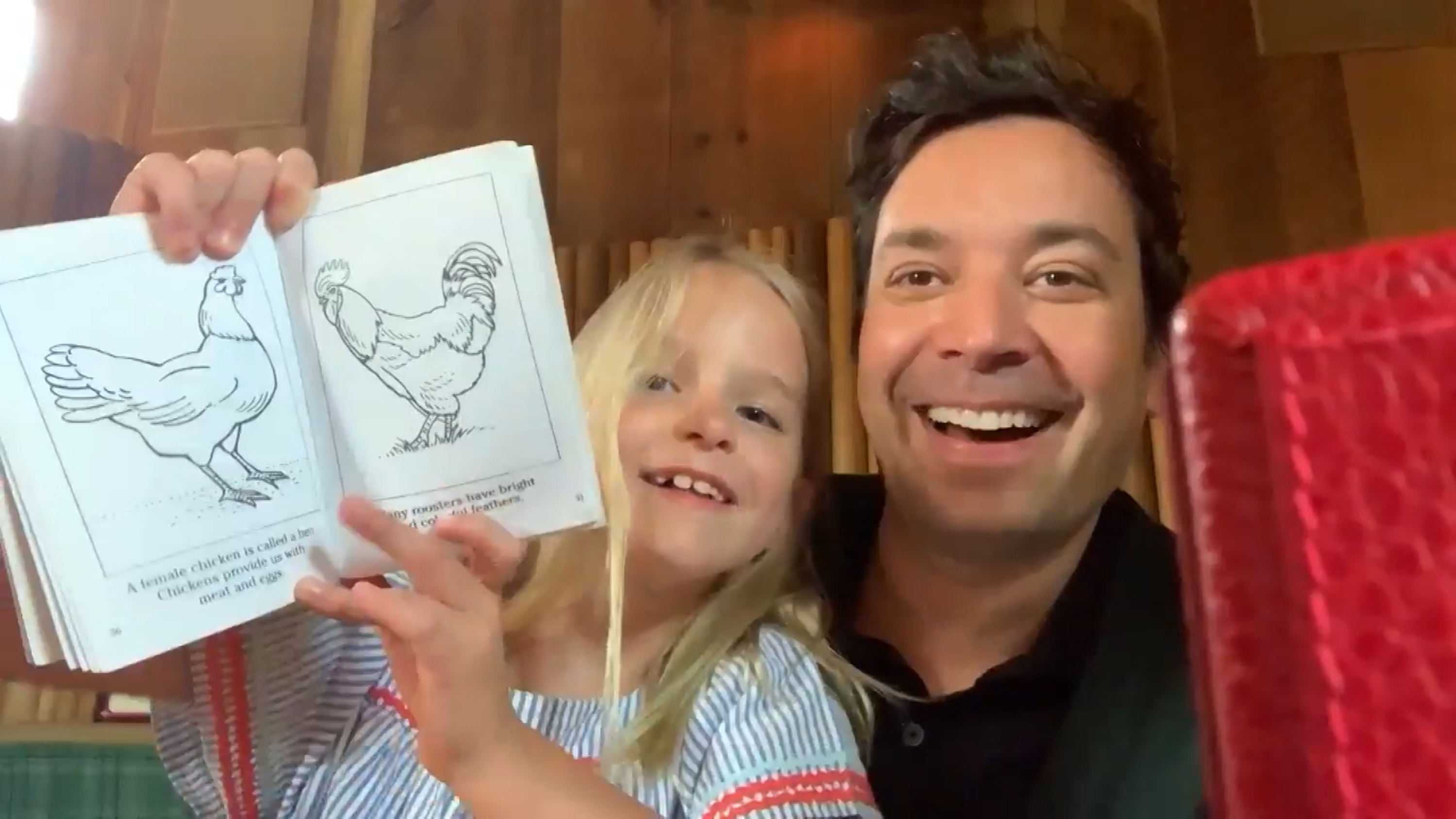 Jimmy Fallon smiles while his daughter, Winnie, holds up a book with chicken illustrations