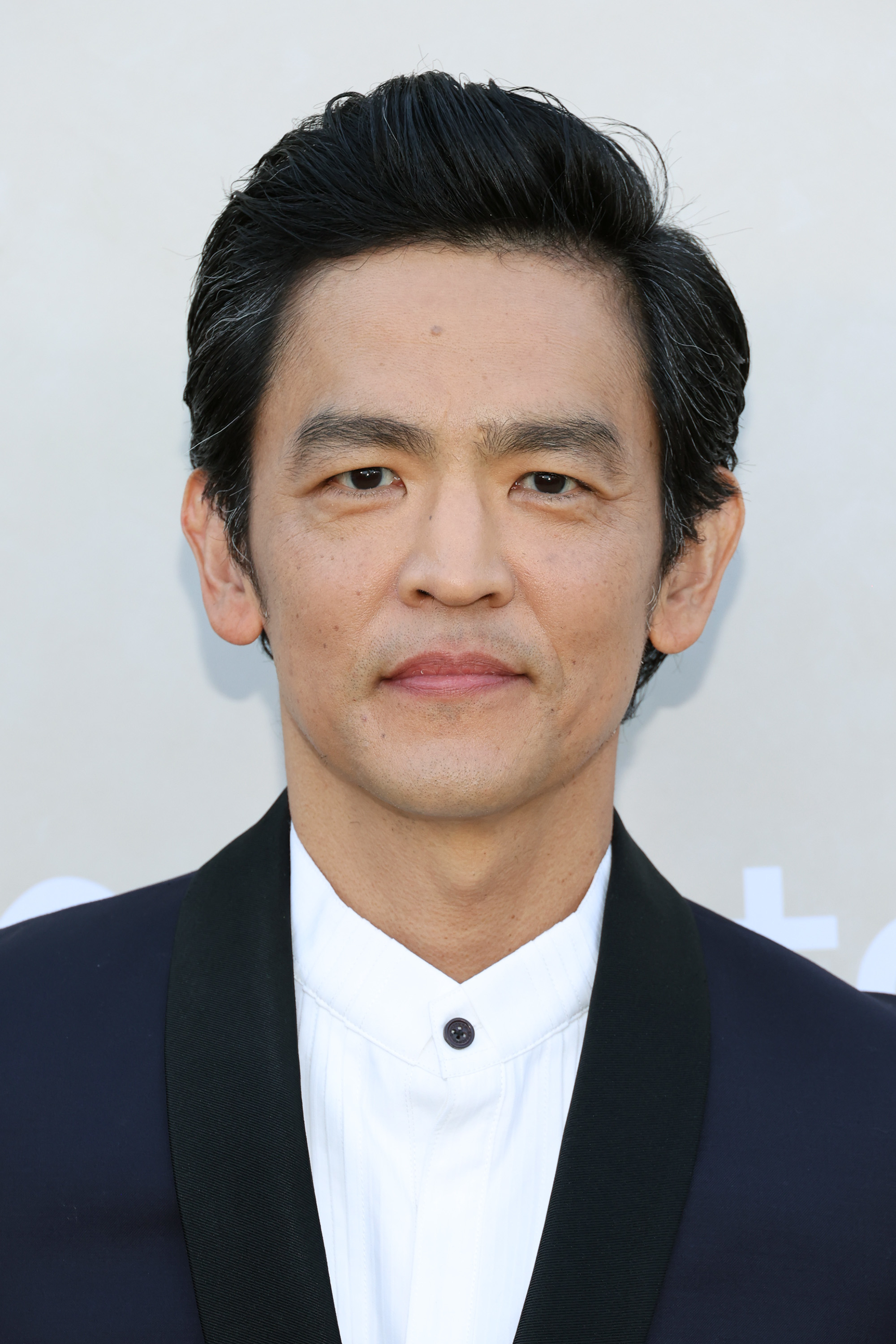 John Cho in a formal suit, posing for a photo on a neutral background