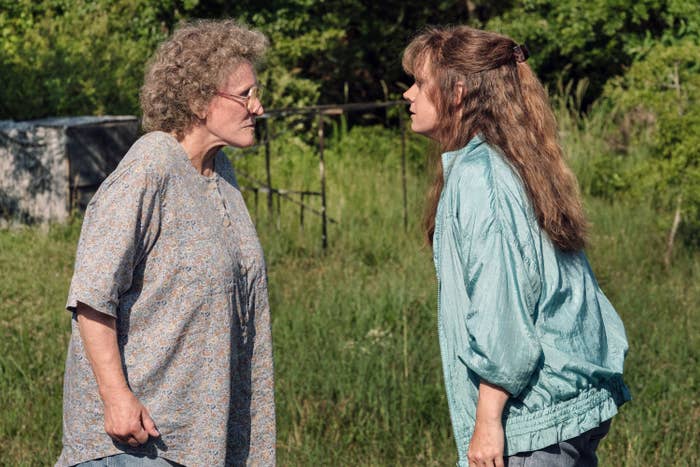 Glenn Close and Amy Adams in a scene from the film "Hillbilly Elegy," wearing casual clothing, stand facing each other with intense expressions in a grassy outdoor setting
