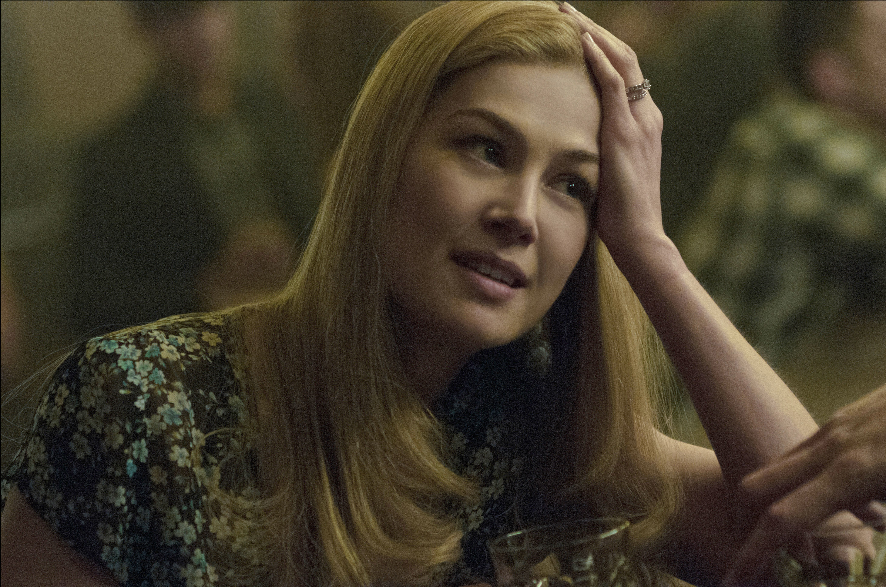 Rosamund Pike sits at a bar, resting her head on her hand, wearing a floral-patterned blouse in &quot;Gone Girl&quot;